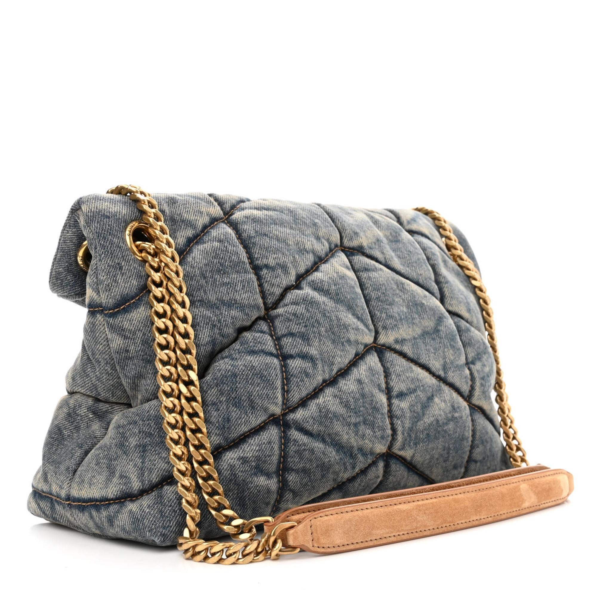 This Saint Laurent shoulder bag is made with signature quilted denim with the iconic ysl logo hardware on the front in gold tone. The bag features an adjustable shoulder strap with a suede pad attached to a chain, top flap with snap closure and two