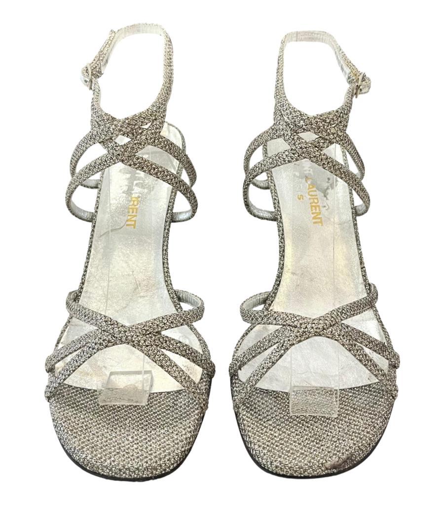 Saint Laurent Strappy Glitter Mesh Sandals
Silver heels crafted in metallic glitter mesh with cross-over strappy design.
Featuring round open toe and buckled ankle strap closure with stiletto heel, leather insoles. Rrp Approx. £680
Size –