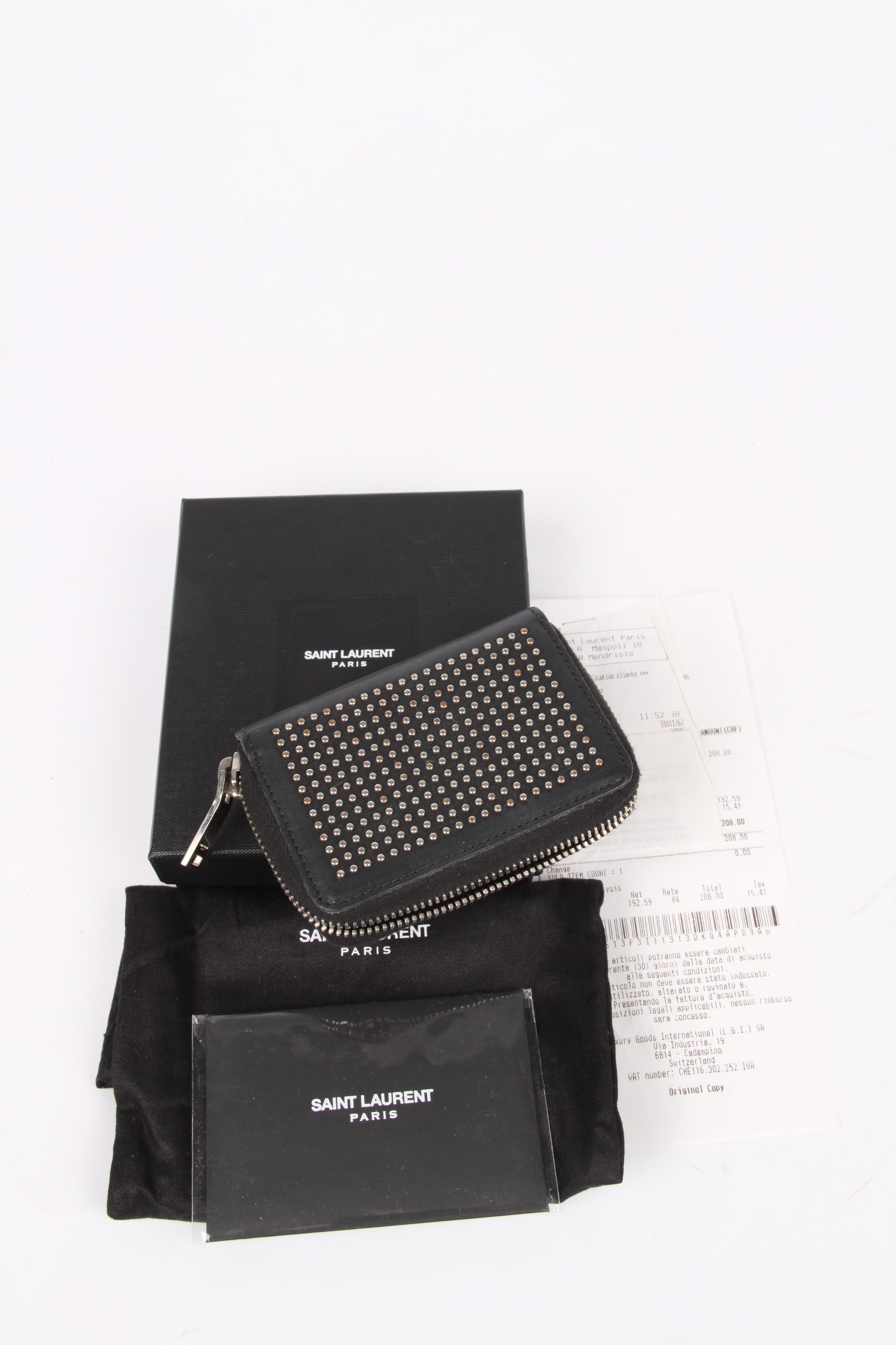 What a cutie! Mini wallet by Saint Laurent covered with silver-tone studs.

Zip-around closure, the interior is crafted from black leather, three small compartments. Tiny model!

On the back a silver-tone SAINT LAURENT PARIS logo.

Has been used,