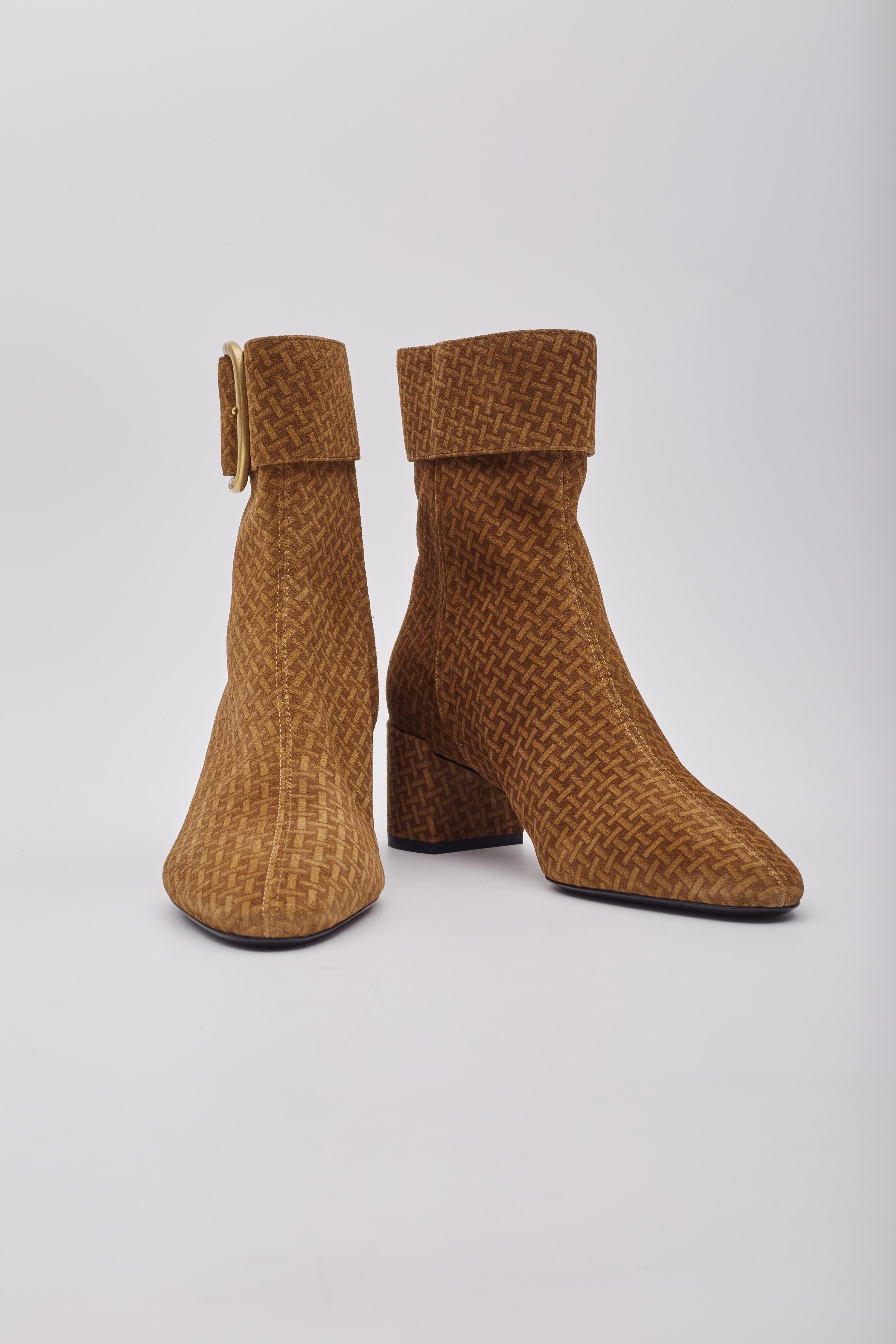 The Saint Laurent booties feature suede leather, a braided pattern printed around the shoe, an almond toe, a buckle and zip with engraving on the buckle and a 50mm heel.

Color: Brown with braided print throughout
Material: Suede leather
Style No.