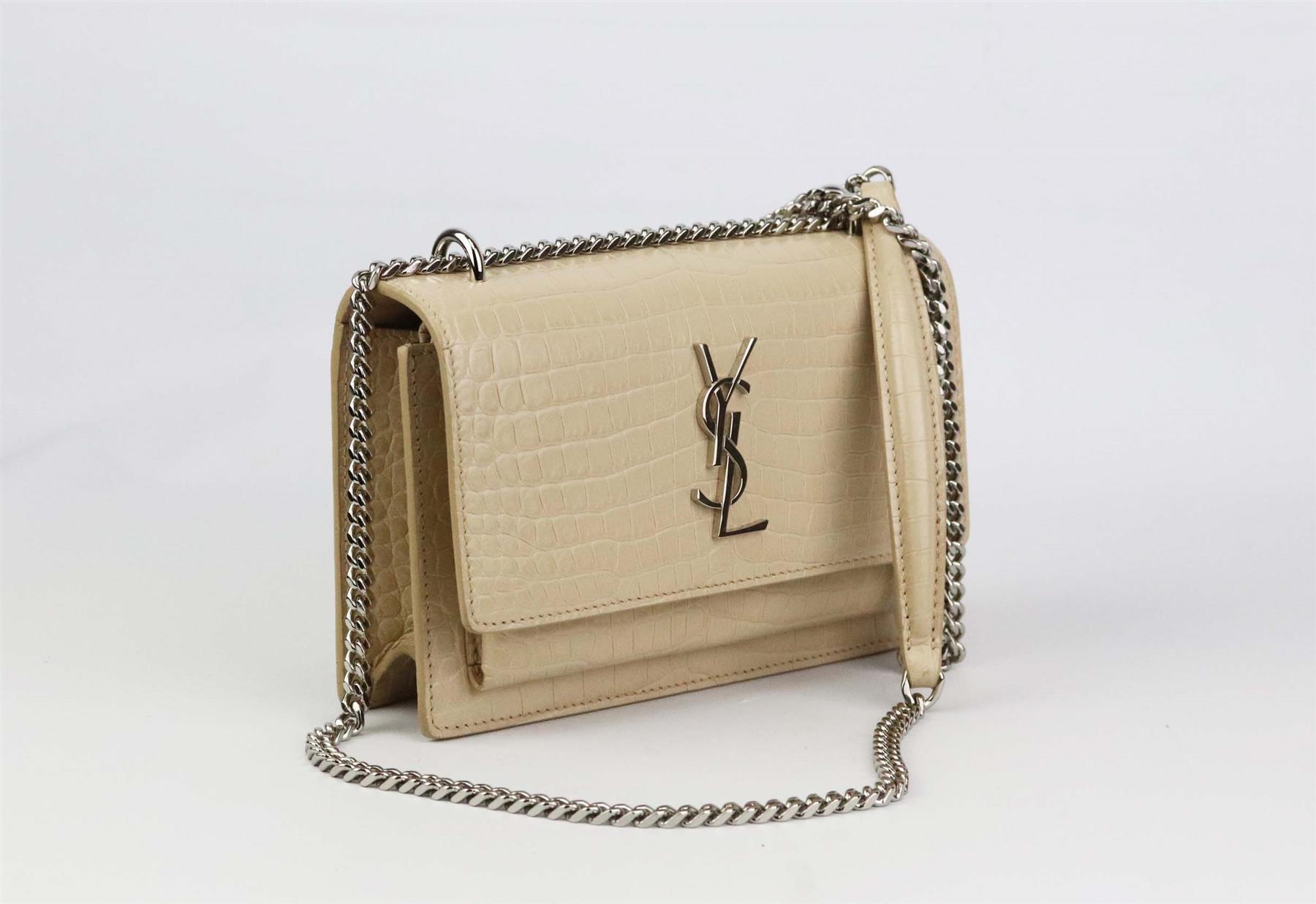 Saint Laurent's 'Sunset' shoulder bag is made from matte beige croc-effect leather, accented with the signature 'YSL' emblem, it opens to reveal a compartmentalized interior with plenty of slots, the silver chain strap can be doubled over or worn