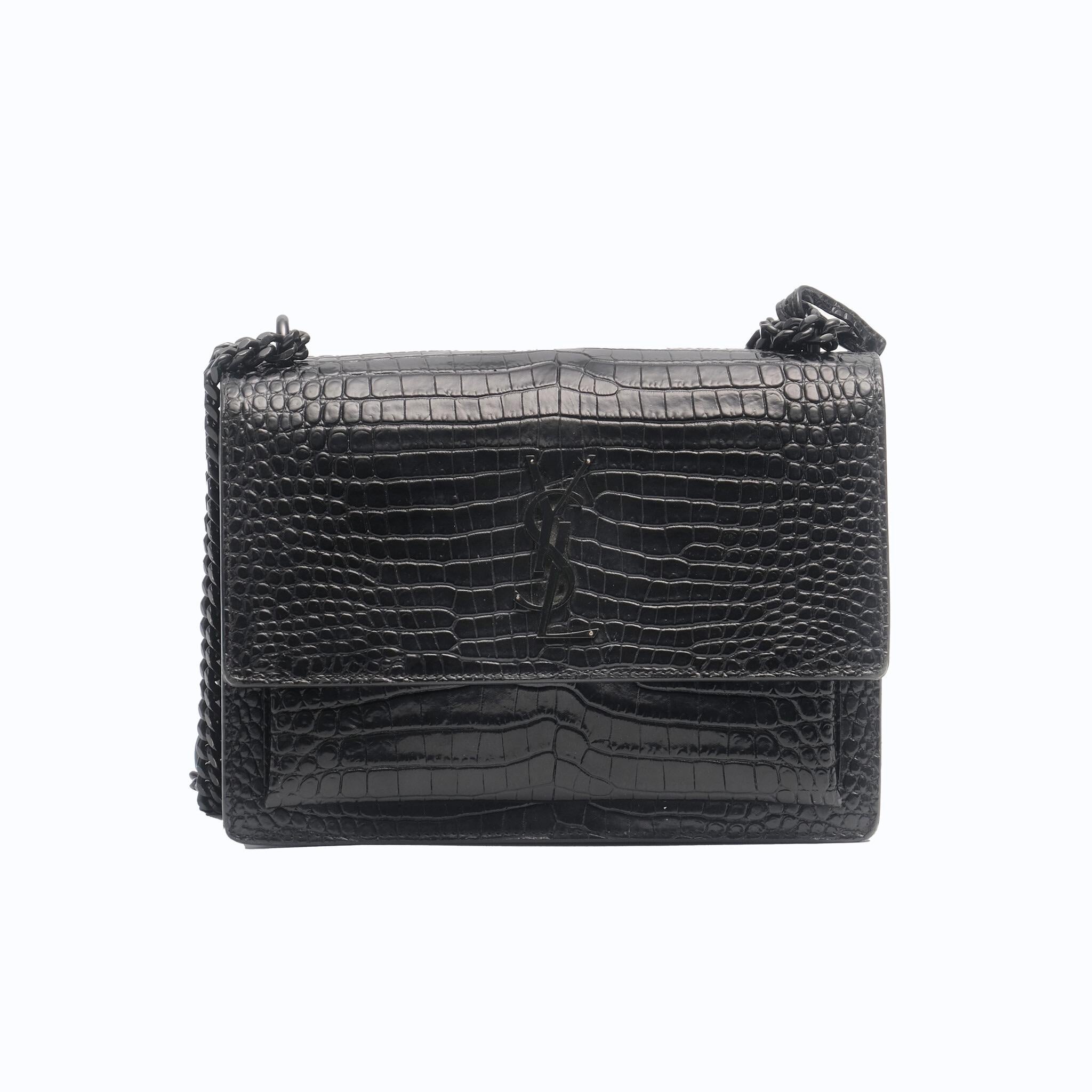The Saint Laurent Medium Sunset Monogram Croc-Embossed Leather Bag is a structured, leather-lined flap bag featuring the iconic Cassandre logo and a detachable leather charm. It is designed with accordion sides and offers a double compartment, a