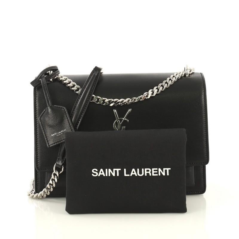 This Saint Laurent Sunset Crossbody Bag Leather Medium, crafted in black leather, features chain link strap with leather pad, accordion sides and silver-tone hardware. Its magnetic snap button closure opens to a black suede interior with two