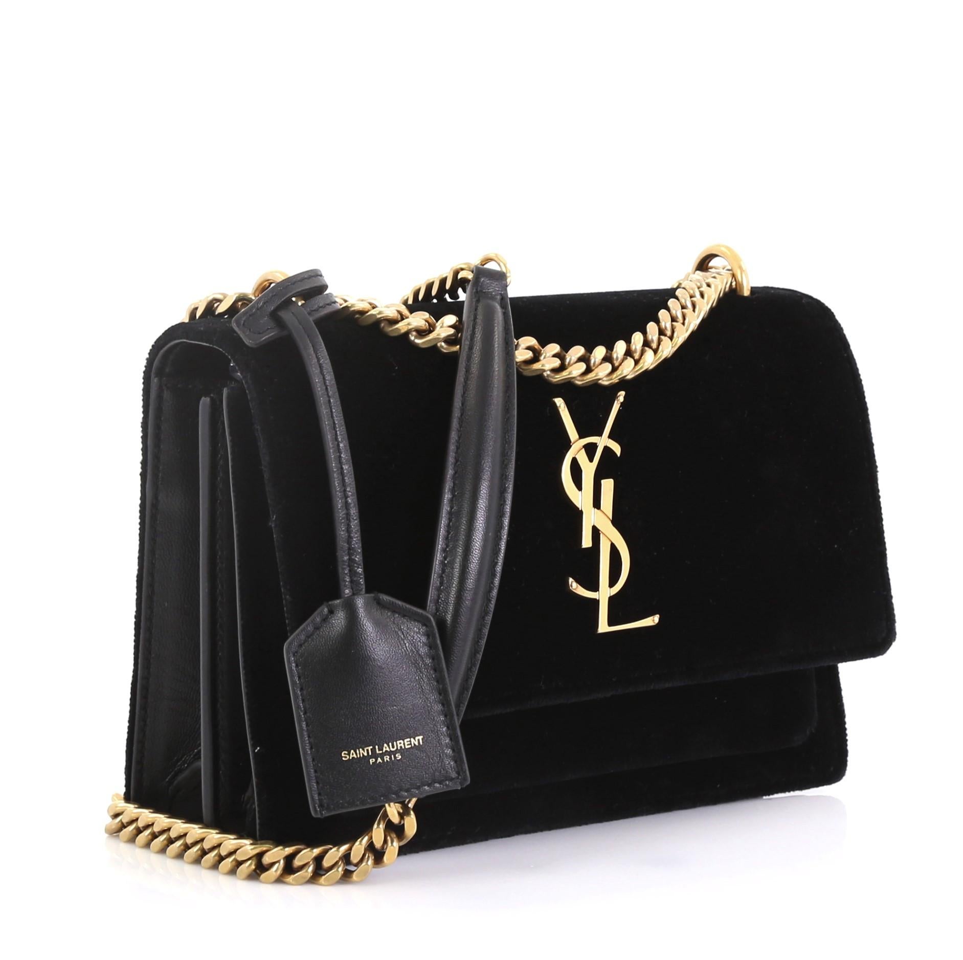 This Saint Laurent Sunset Shoulder Bag Velvet Small, crafted in black velvet, features a chain link strap with leather pad, interlocking YSL logo at its center, and aged gold-tone hardware. Its magnetic snap button closure opens to a black leather