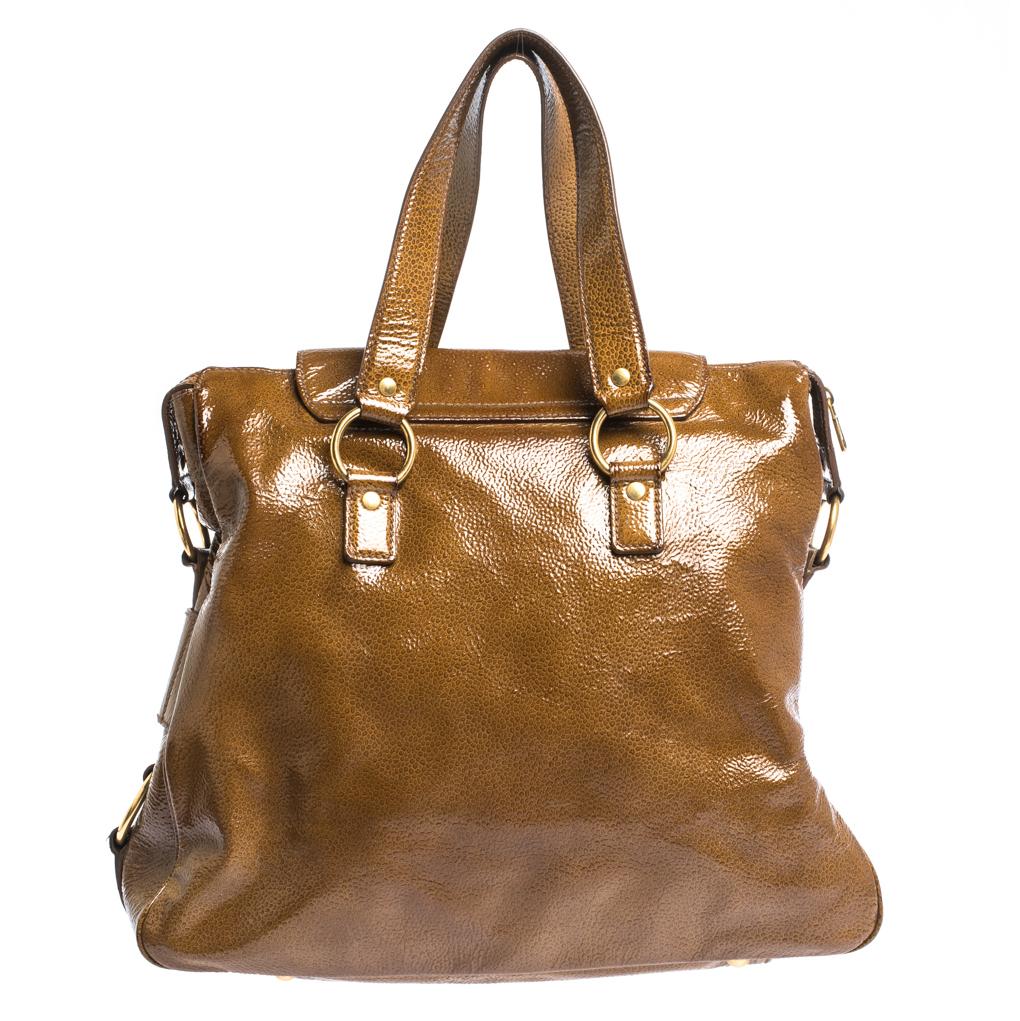 Carry your essentials in this catchy tan-colored Muse bag by Saint Laurent. Crafted in patent leather, this pretty and practical bag features dual handles and a shoulder strap. The studs at the bottom serve to prevent it from scratches and scuffs. A