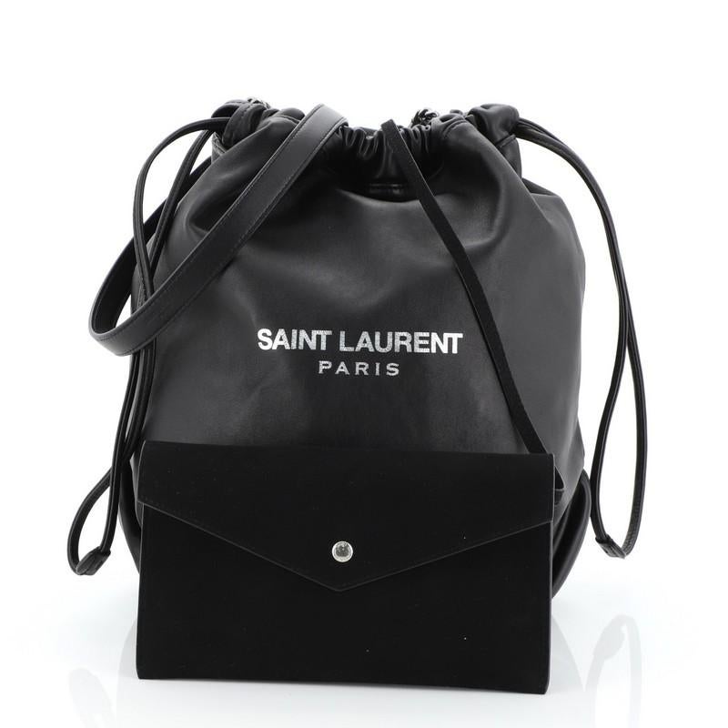 This Saint Laurent Teddy Bucket Bag Leather Small, crafted from black leather, features chain link strap with leather pad, logo print at center front, and matte silver-tone hardware. Its drawstring closure opens to a black microfiber interior.
