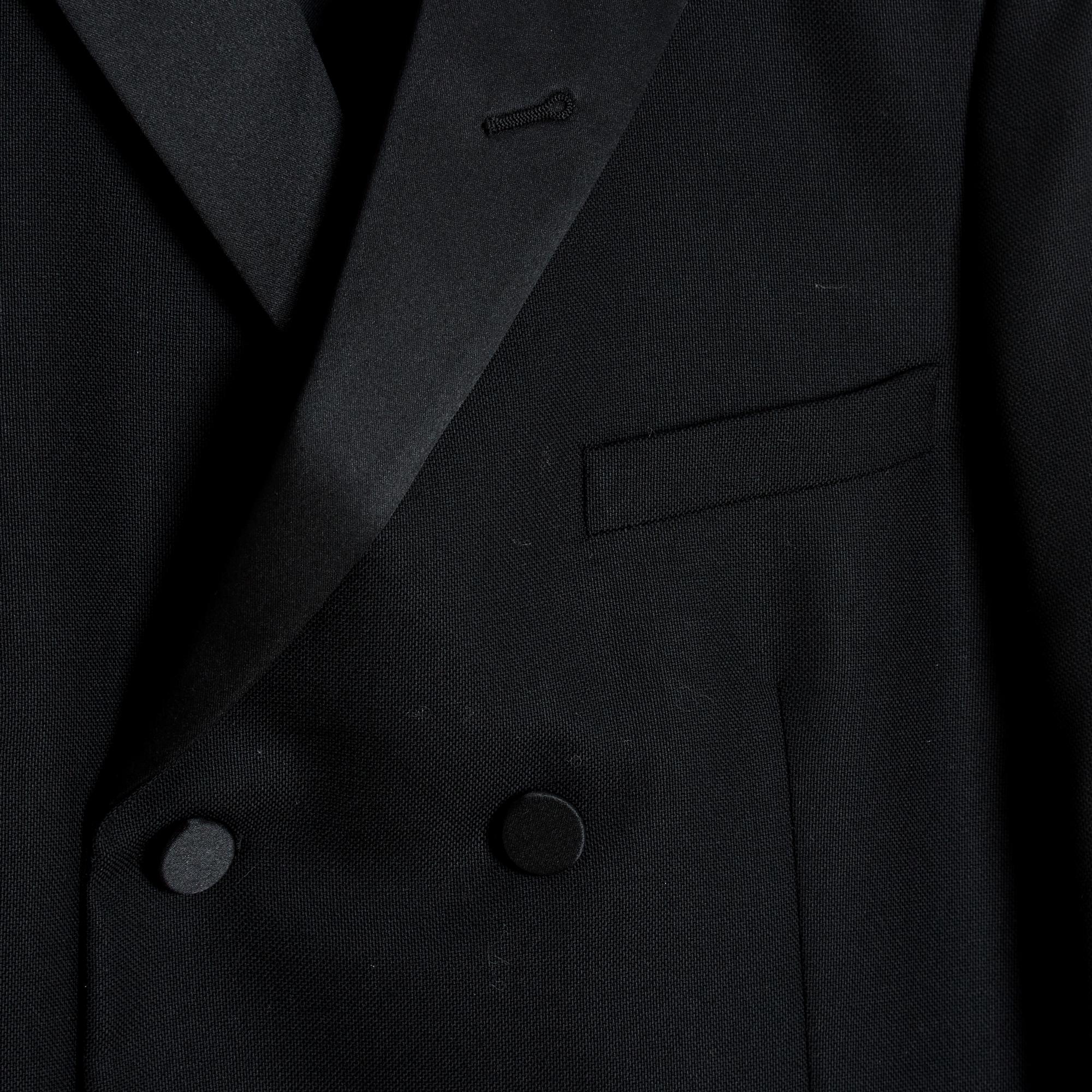 Saint Laurent jacket from the AW2012 collection by Hedi Slimane in black wool cloth, straight cut, notched collar dressed in black satin and closed by double-breasted buttons (buttons dressed in satin), chest pocket, 2 flap pockets, long sleeves