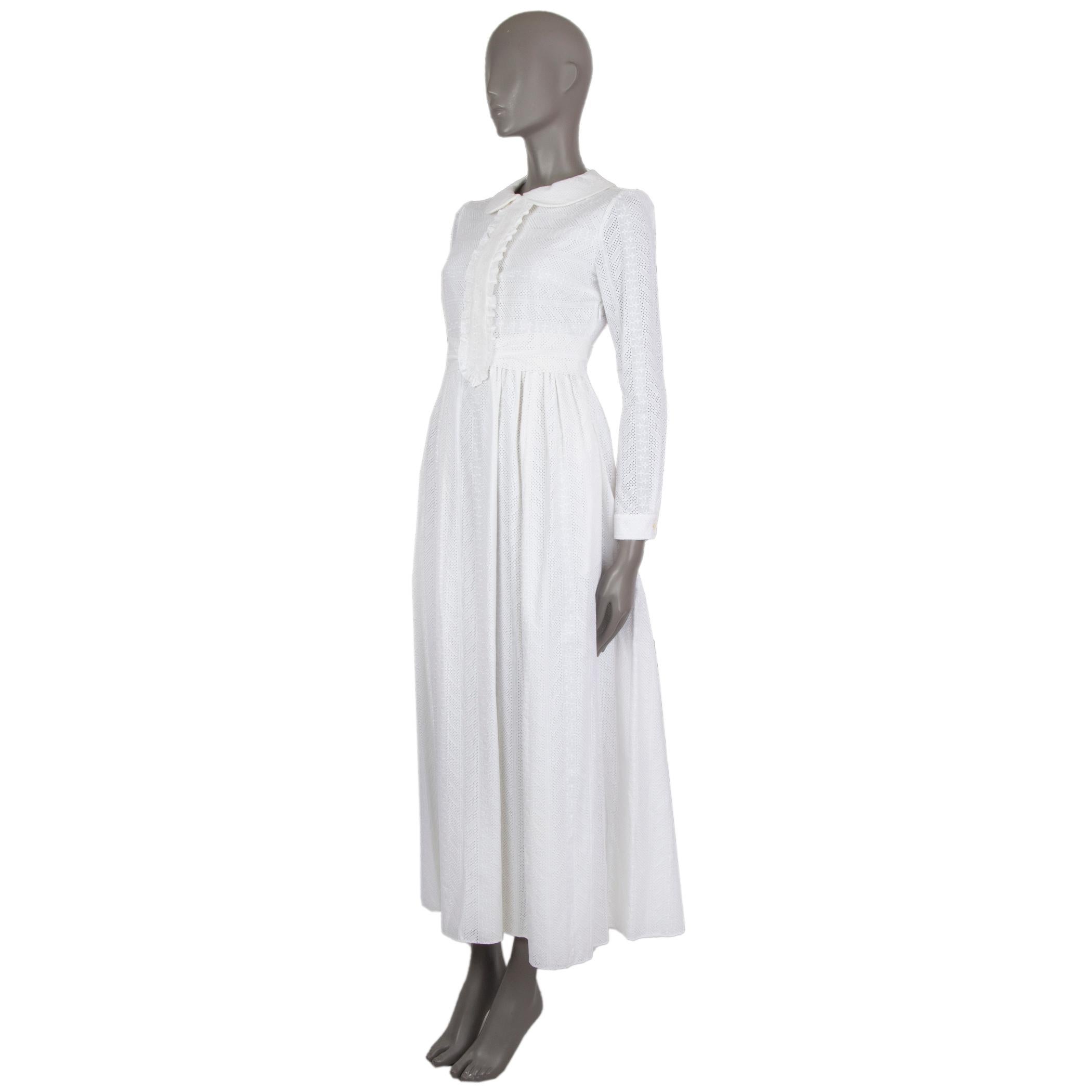 Saint Laurent long-sleeve 'Broderie Anglaise' maxi dress in off.white cotton. With Peter-Pan collar, ruffled panel on the front, attached waistband, pleated skirt, and one-button square cuffs. Closes with concealed buttons on the front, invisible