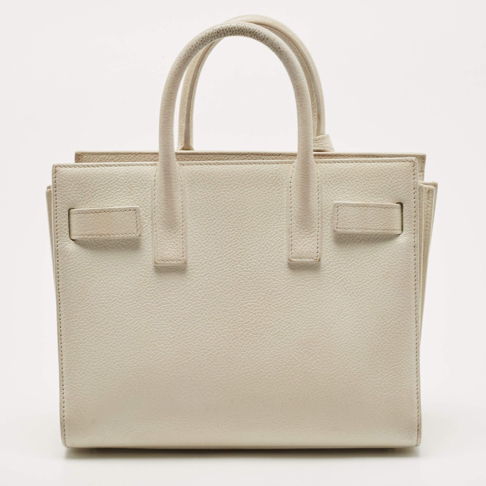 Diese Sac de Jour von Saint Laurent hat eine Struktur, die für Raffinesse steht. Die aus weißem Leder gefertigte Tasche wird von doppelten oberen Griffen und einem Schulterriemen gehalten. Der gefütterte Innenraum bietet genügend Platz für Ihre