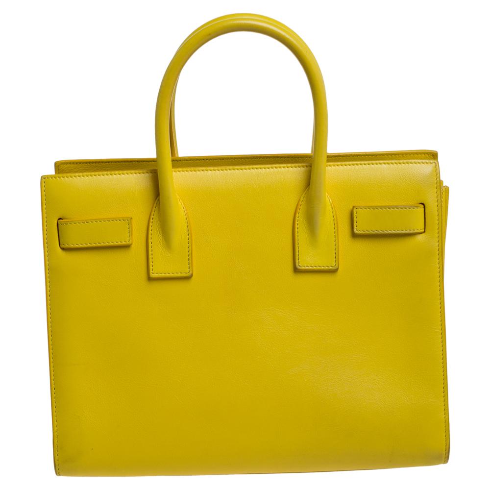 This Sac de Jour tote by Saint Laurent has a structure that simply spells sophistication. Crafted from leather in a yellow hue, the bag is held by double top handles. The tote comes with a leather-lined interior with enough space to store your