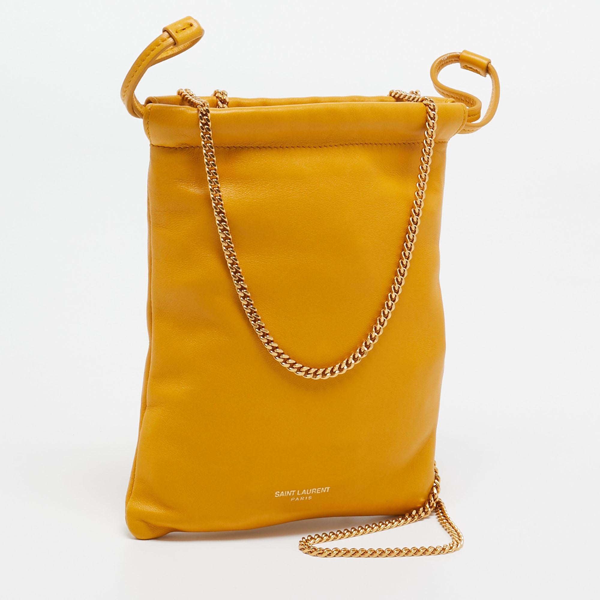 The Saint Laurent phone holder crossbody bag is a chic accessory crafted from luxurious yellow leather. Compact and functional, it features a sleek design, a secure phone compartment, and a crossbody strap for convenient hands-free wear, embodying