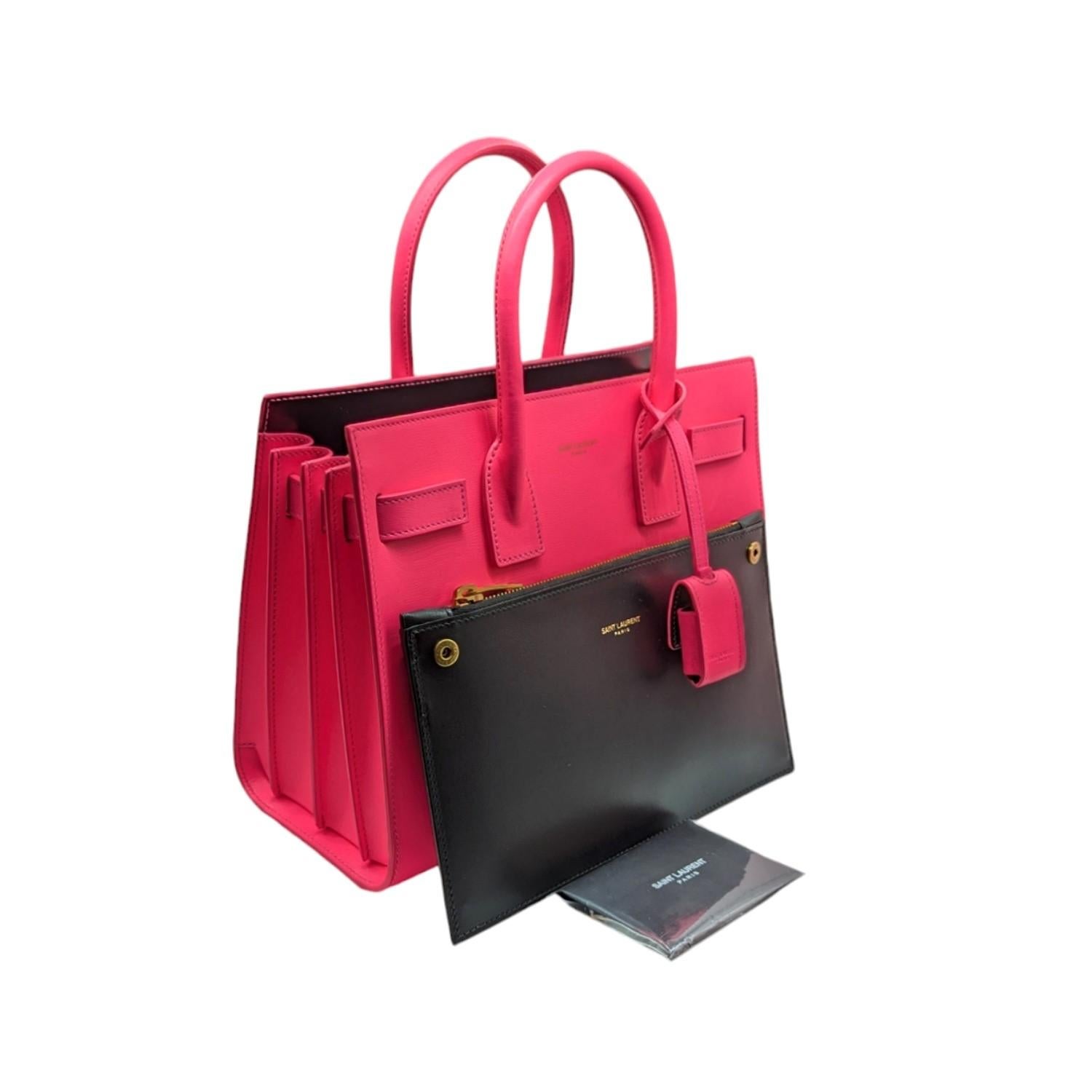 This structured handbag is crafted of smooth calfskin leather in pink. The bag features accordion style sides, rolled leather top handles, and bronze hardware. The top opens to a tonal leather interior with a removable zip pouch.

Designer: YVES