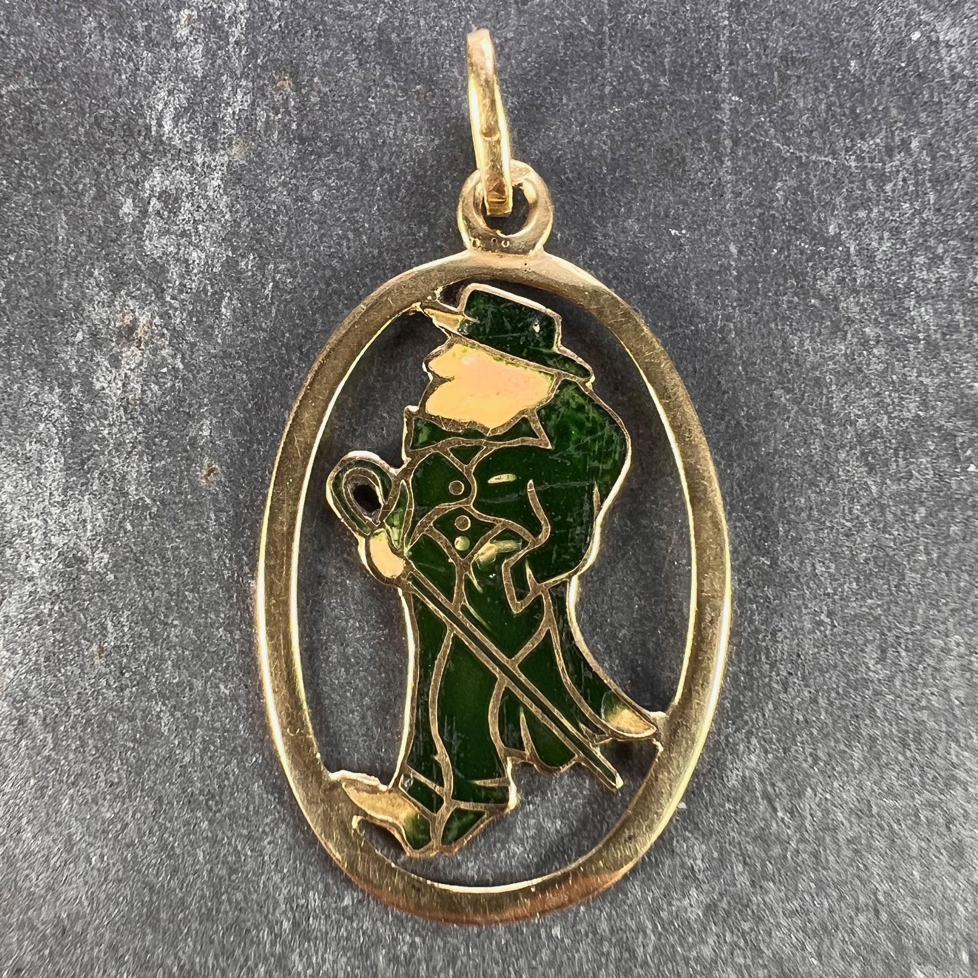 An 18 karat (18K) yellow gold charm pendant set with green and cream enamel designed as Saint Patrick of Ireland dressed as a man in a green suit with tailcoat, hat and cane. Stamped with the owl mark for 18 karat gold and French import and K18 to