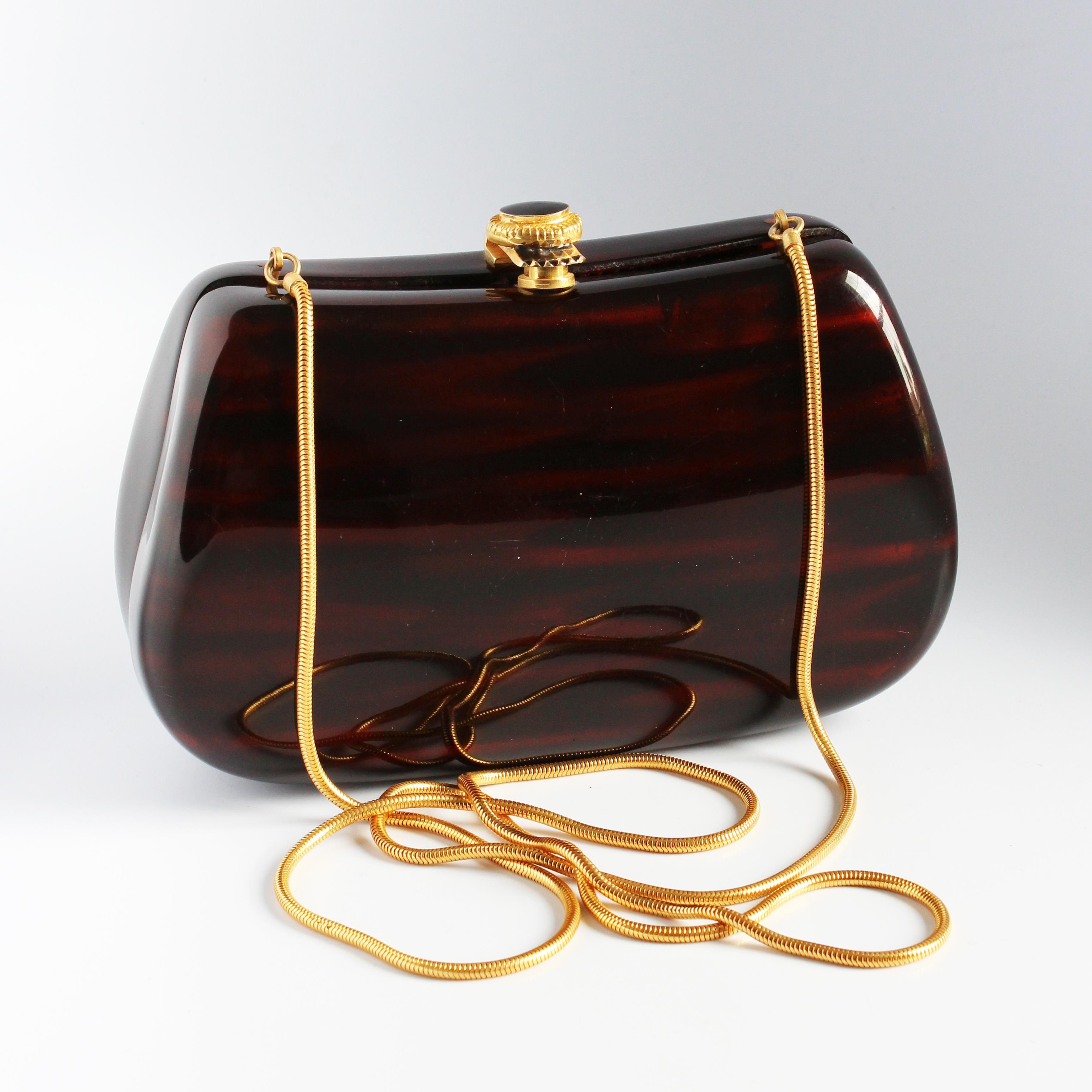 Vintage evening bag or minaudière, made for Saks Fifth Avenue, most likely in the late 1960s.  Made from polished resin made to resemble wood, it features a decorative gold metal and enamel clasp closure and a gold coil chain that can be used for