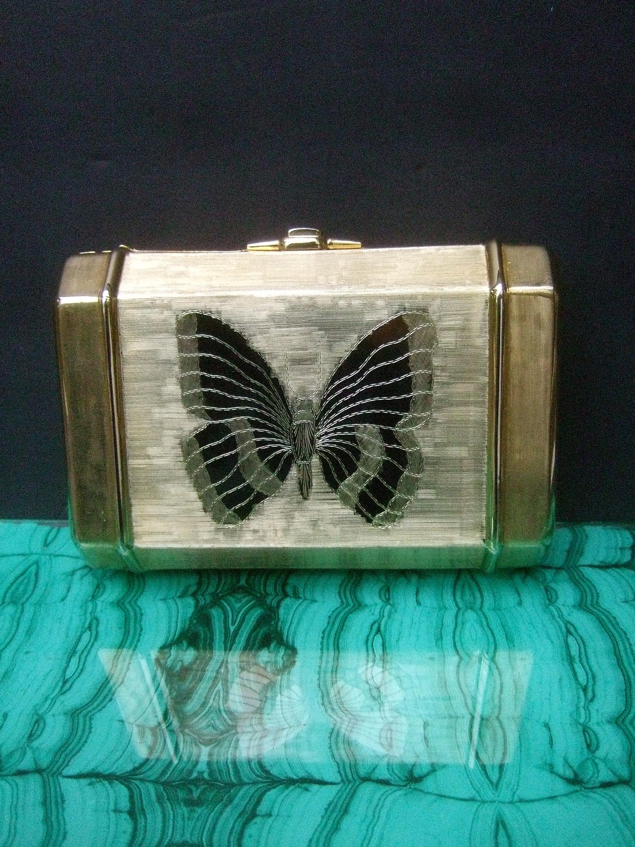Saks Fifth Avenue Opulent gilt metal butterfly minaudiere' c 1970s
The elegant evening bag is adorned with an etched butterfly motif on the front
The stylized butterfly is shiny polished gilt metal; in contrast the sides and backside are