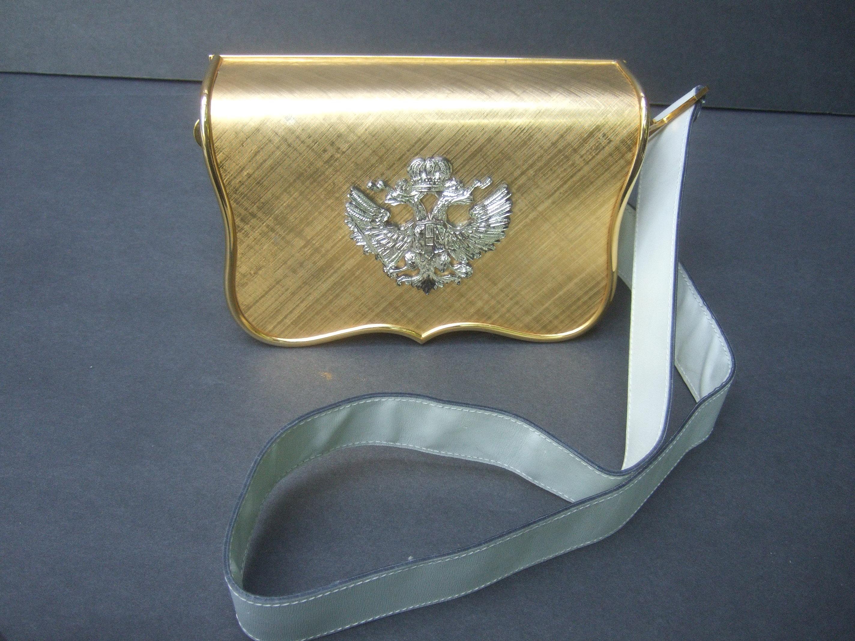 Saks Fifth Avenue Italian gilt metal eagle emblem white leather shoulder bag c 1970s
The unique handbag is adorned with an ornate silver metal double headed eagle
medallion mounted onto the brushed gold metal flap cover

The structured gilt metal
