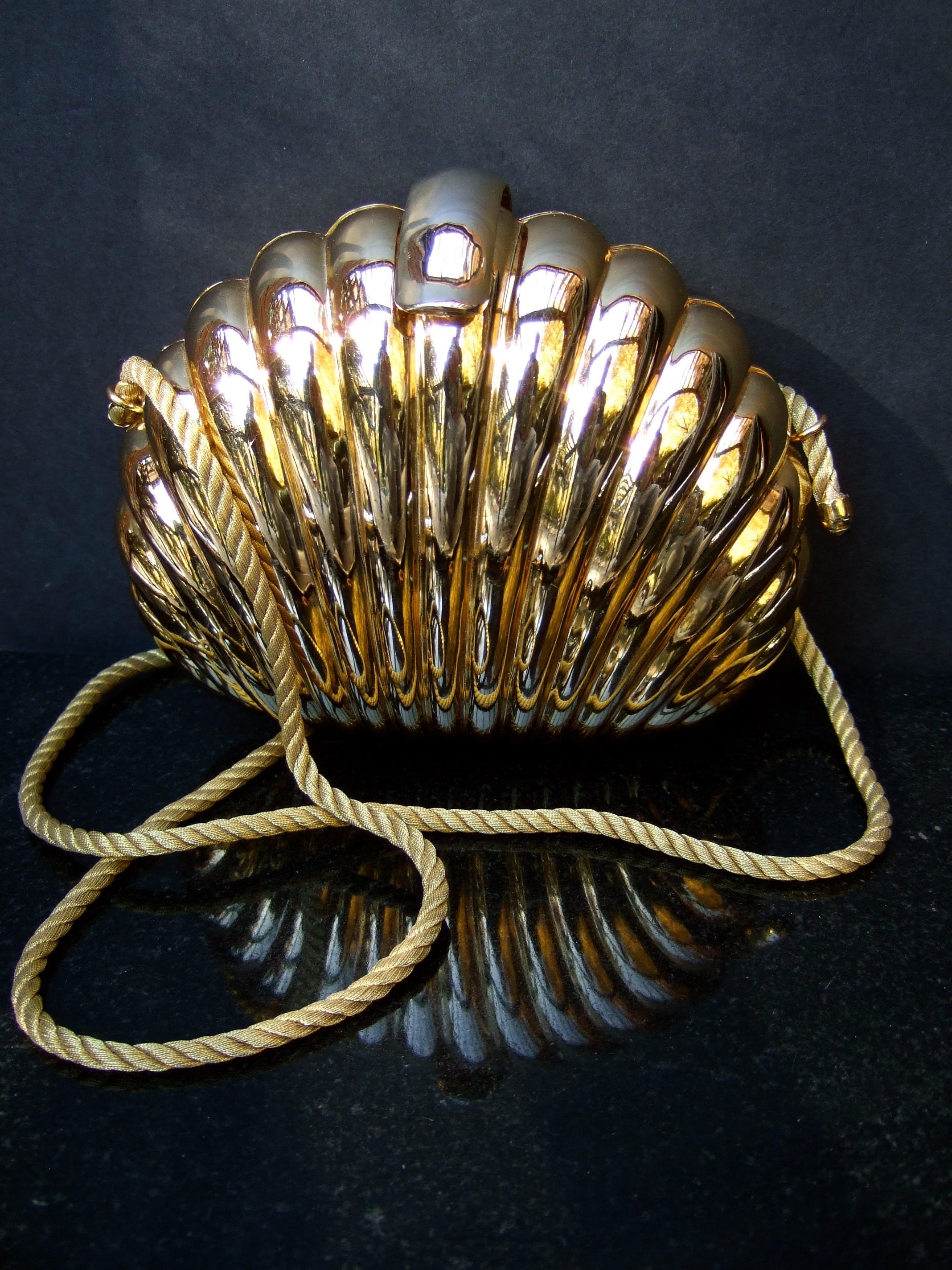 Saks Fifth Avenue Italian gilt metal minaudiere' evening bag c 1980
The elegant grooved gold metal shoulder bag has a clam shell 
structured design

Paired with a golden braided rope shoulder strap that is stationary
 on the exterior.  The interior