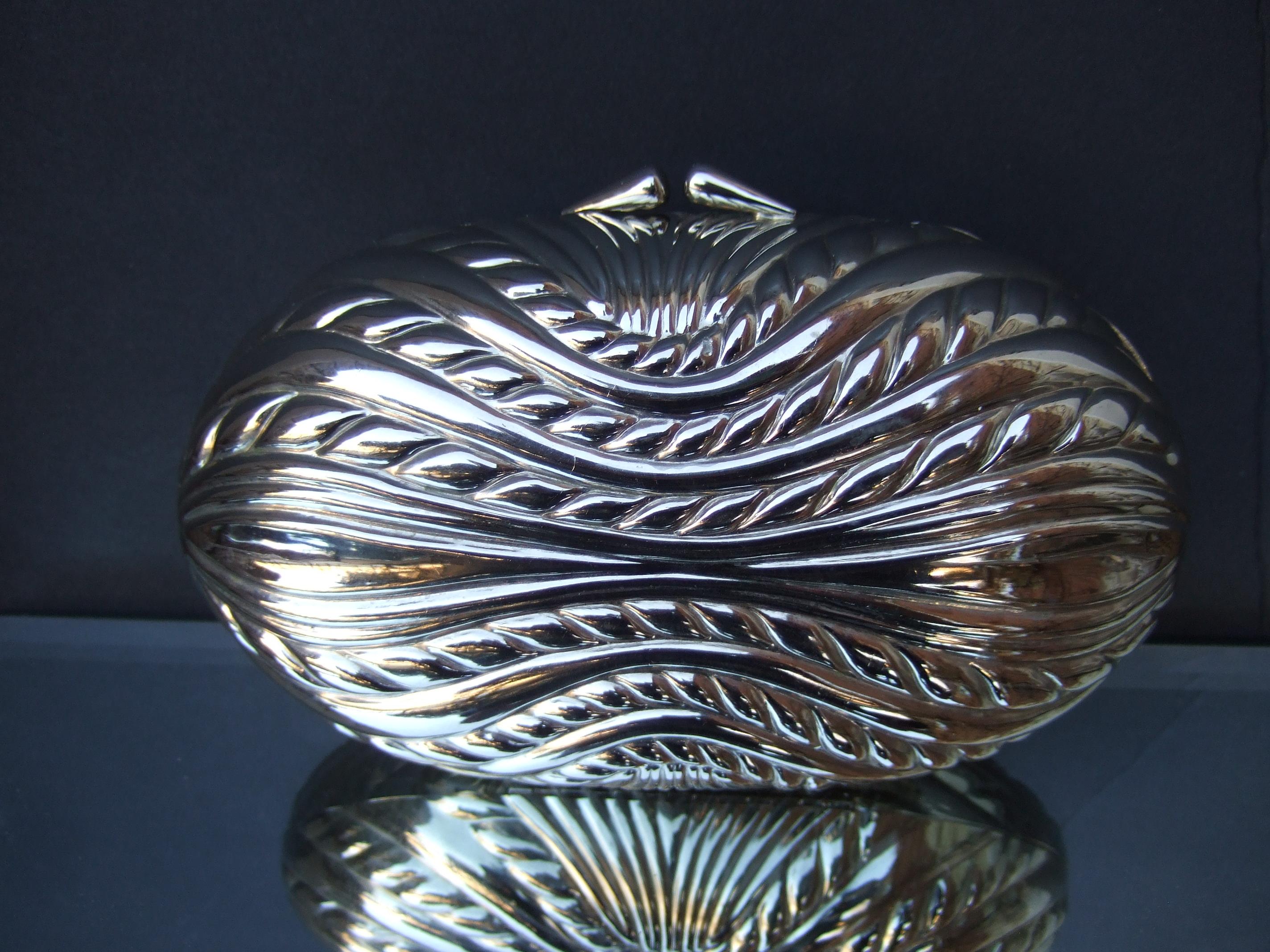 SAKS FITH AVENUE Italian silver metal minaudiere' clutch - shoulder bag c 1970s 
The elegant oval shaped metal evening bag is embellished with impressed sinuous 
designs on both exterior sides

The versatile evening bag transitions from a chic