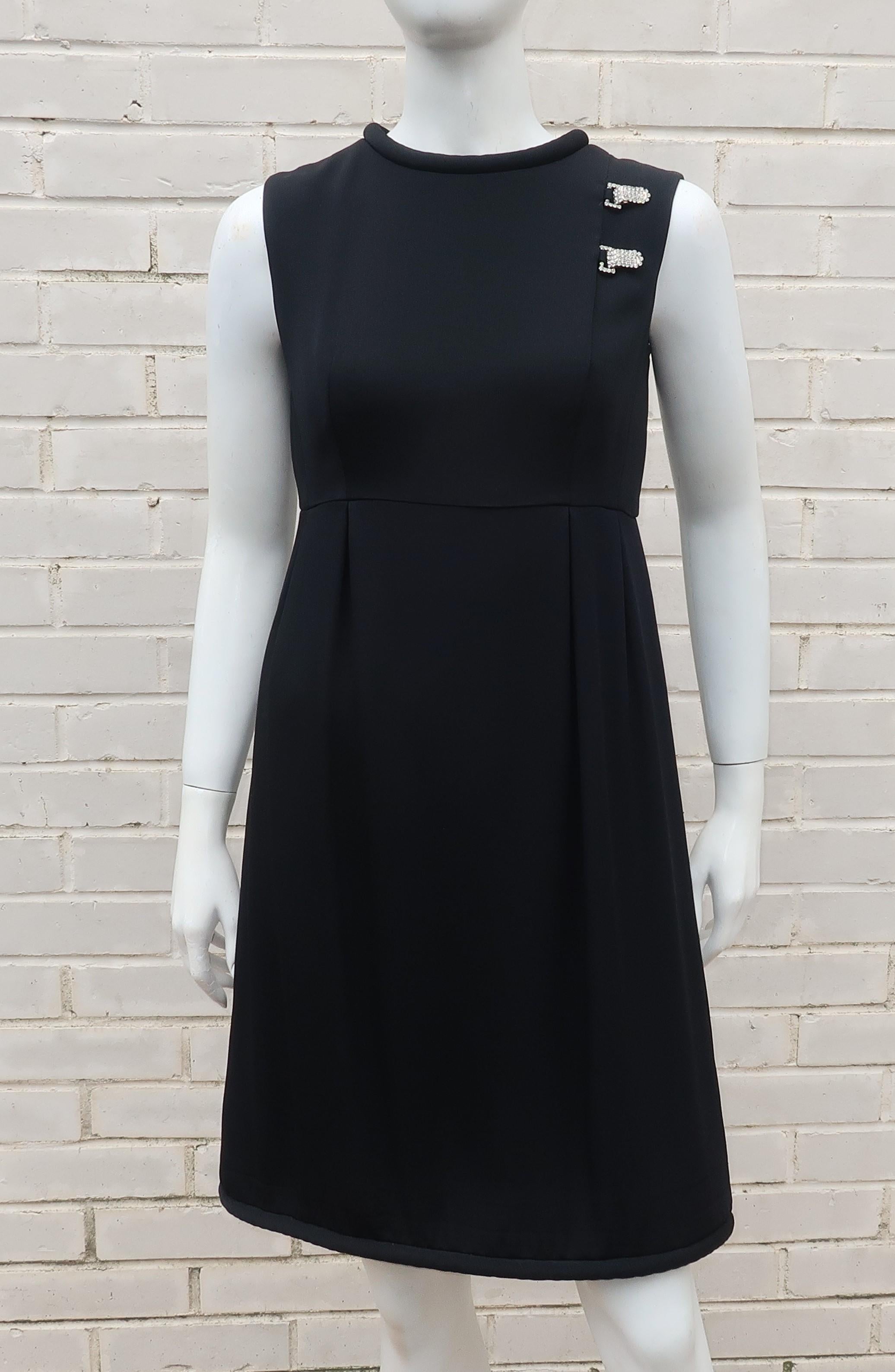 Saks Fifth Avenue youthful 1960's mod version of a classic 'little black dress' in a black crepe fabric that appears to be silk with rhinestone embellishments in the form of faux clip buckles.  The fabric is lined and hemmed with padded cording