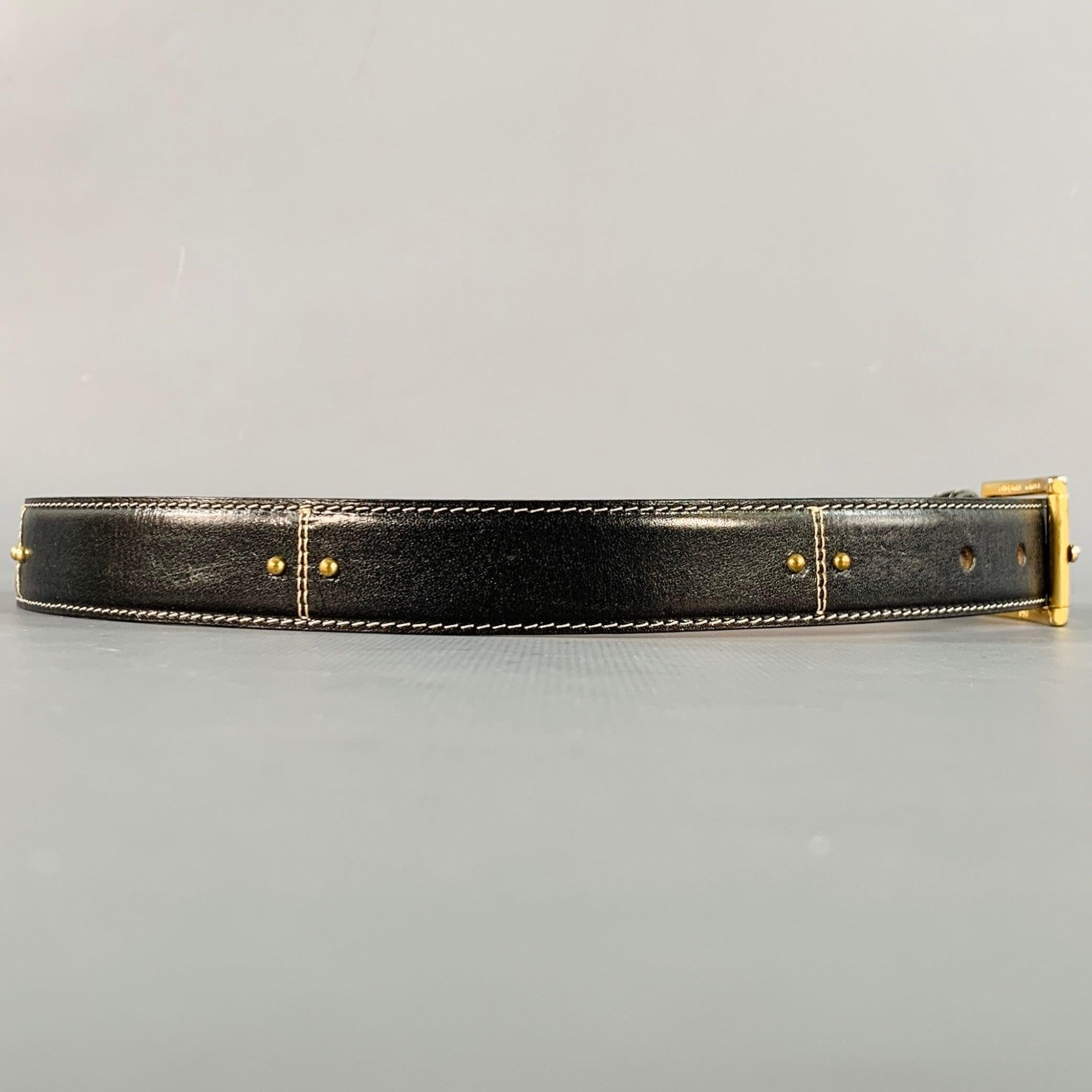 SAKS FIFTH AVENUE belt in a black leather featuring a gold tone metal studded design, and gold tone metal buckle closure. Made in Italy.Excellent Pre-Owned Condition.  

Marked:   MLength: 32 inches Width: 0.75 inches Fits: 25 inches  - 29 inches