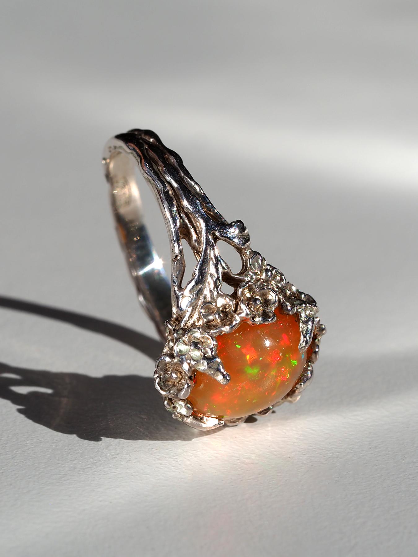 Sakura Opal – Sterling Silver Ring
An original artisan creation showcasing a luminous Ethiopian opal of exceptional fire, set in intricately sculpted sterling silver. The design evokes blossoming branches of sakura, wrapping gracefully around the