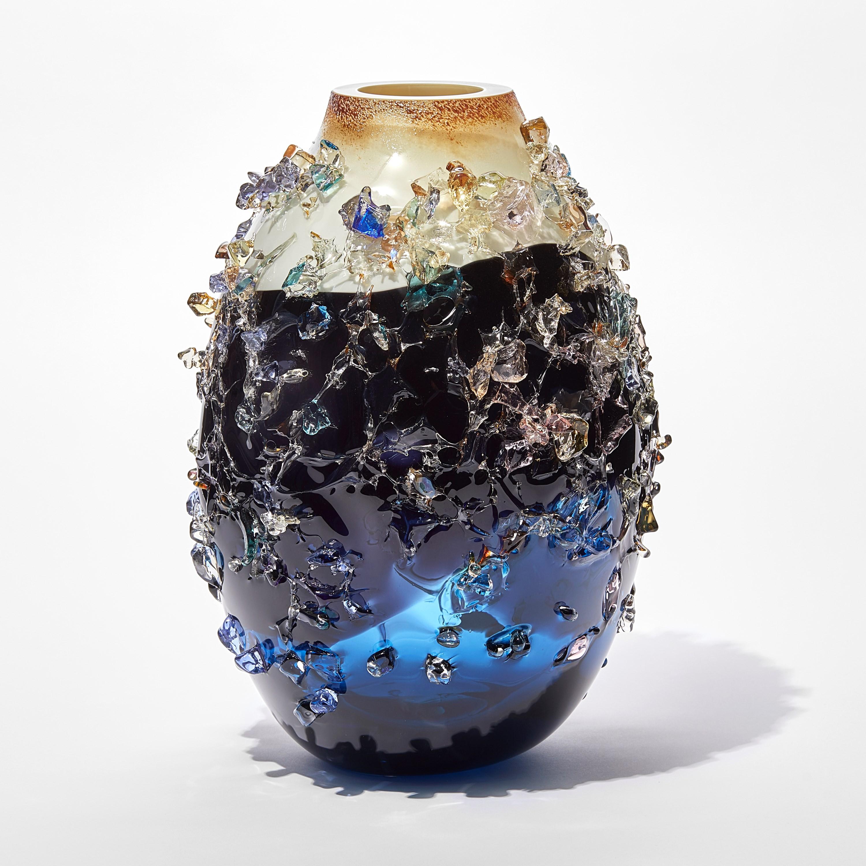 Sakura TFO23031 ist eine einzigartige blaue, indigoblaue, cremefarbene und mehrfarbige Vase aus mundgeblasenem, skulpturalem Kunstglas, die mit organischen Glasscherben des niederländischen Künstlers Maarten Vorlijk verziert ist. Das Stück ist