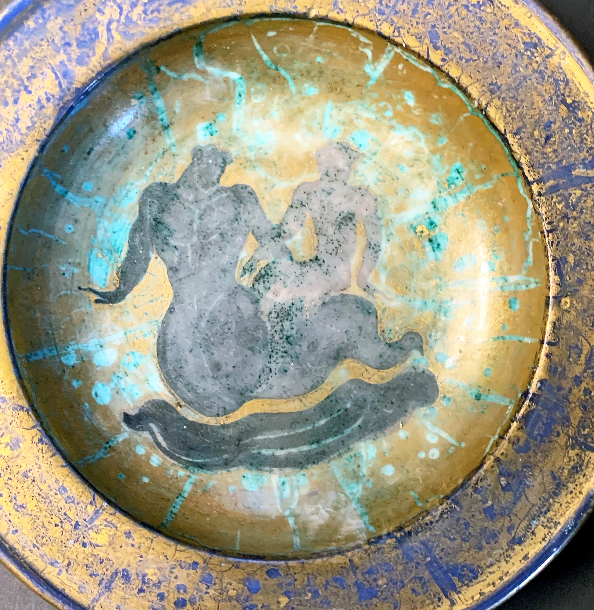 Vividly glazed in tones of jade, cobalt blue, gold and charcoal, this remarkable, high-style Art Deco bowl was created by Jean Mayodon, the great Art Deco sculptor and ceramicist. The bowl depicts Neptune and Salacia, gliding along an Art Deco sea,