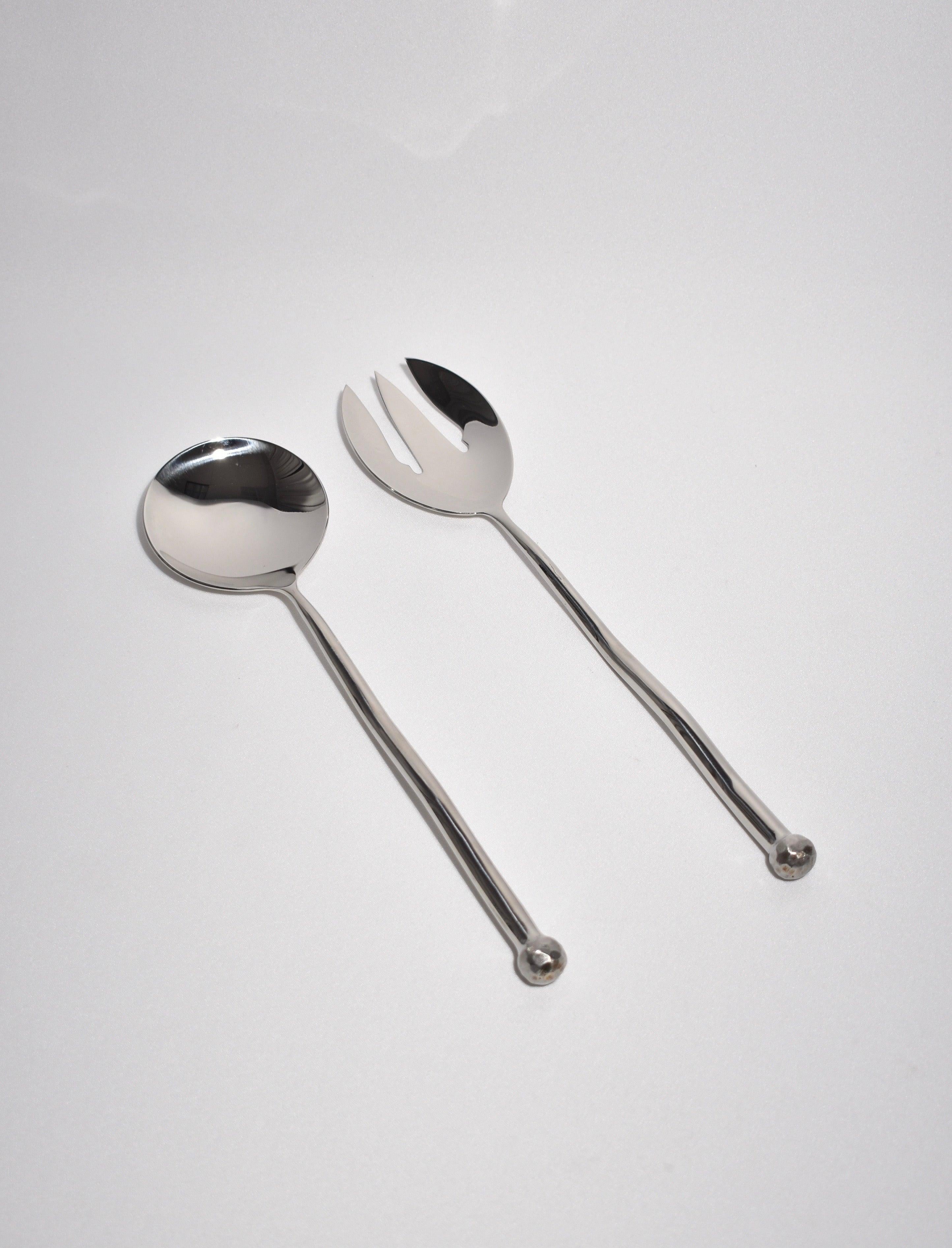 Sculptural, large stainless steel salad serving set in sphere pattern. Each piece features an undulating handle and hammered textured knob on end. Impressed above knob on underside of handle: 'IZABEL LAM'. 

Dimensions: 
Serving Spoon, 12