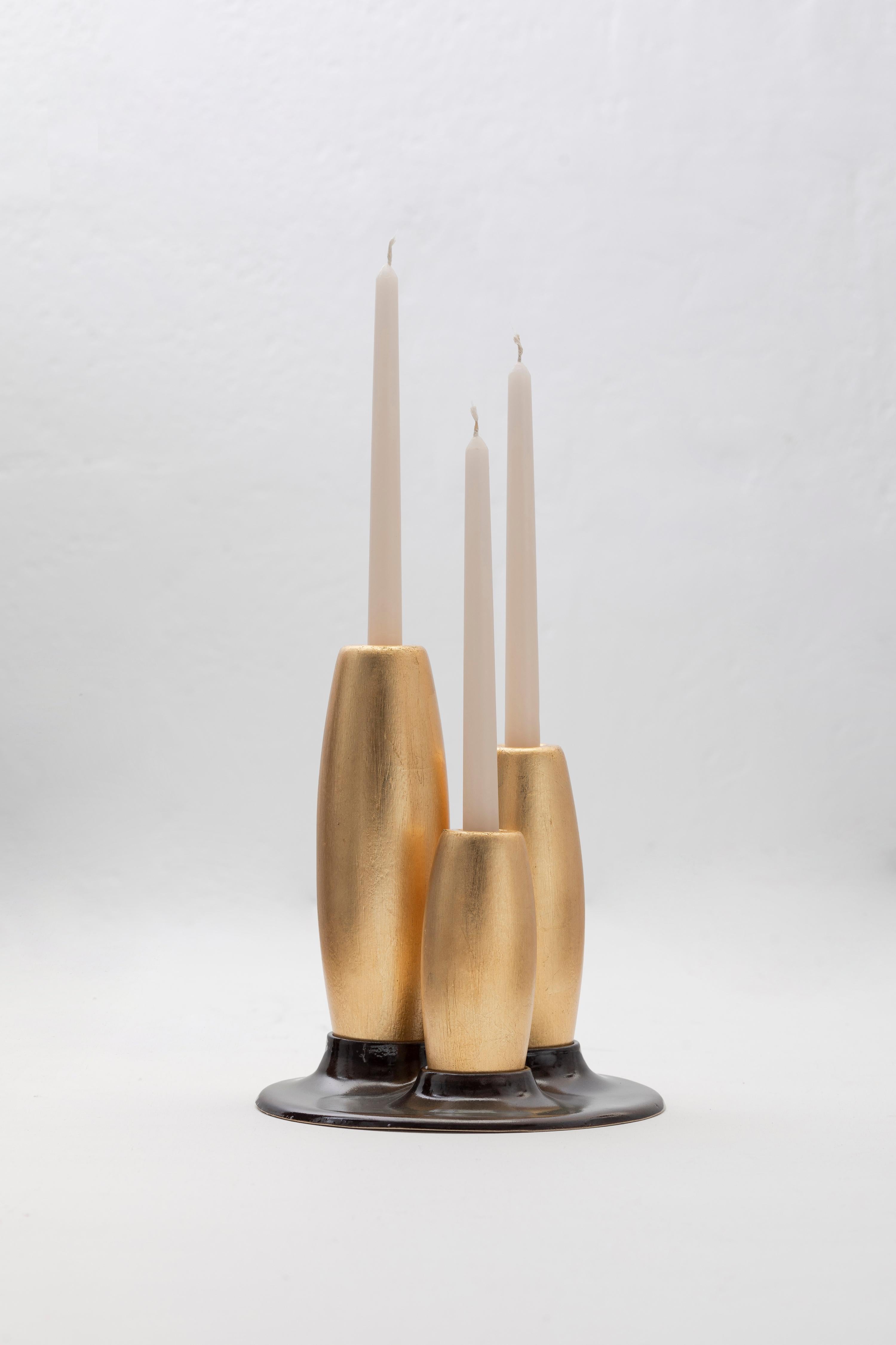 Decorative candleholder with slip casted ceramic base, and solid seike wood lathed plynths in Ébano or Gold Leaf finish.

Crafted with precision, these candle holders feature slipcasted ceramic adorned with a matte black glaze, providing both