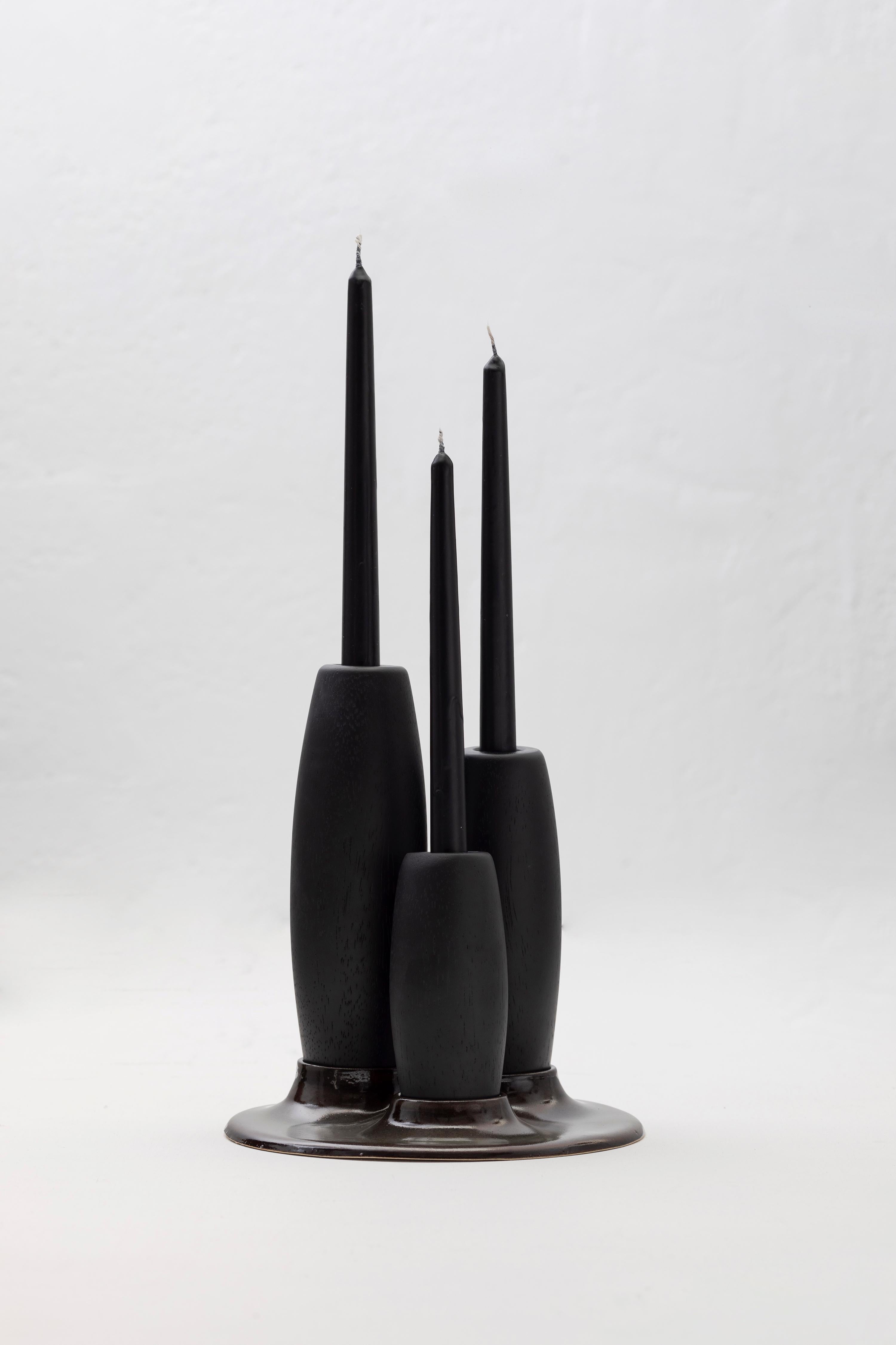 Decorative candleholder with slip casted ceramic base, and solid seike wood lathed plynths in Ébano or Gold Leaf finish.

Crafted with precision, these candle holders feature slipcasted ceramic adorned with a matte black glaze, providing both
