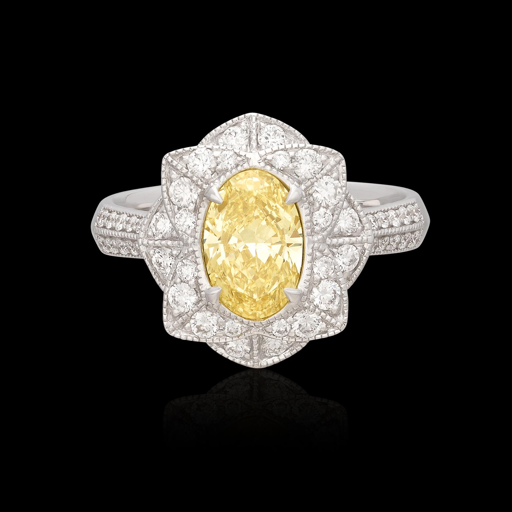 Bring in the sunshine with this lovely Salavetti yellow diamond ring! It centers an oval shaped diamond, weighing 1.35 carats, and measuring 9.0 x 5.9 x 3.15mm, a lovely lemon yellow color and VS2 clarity, it sits within a flower of 46 round