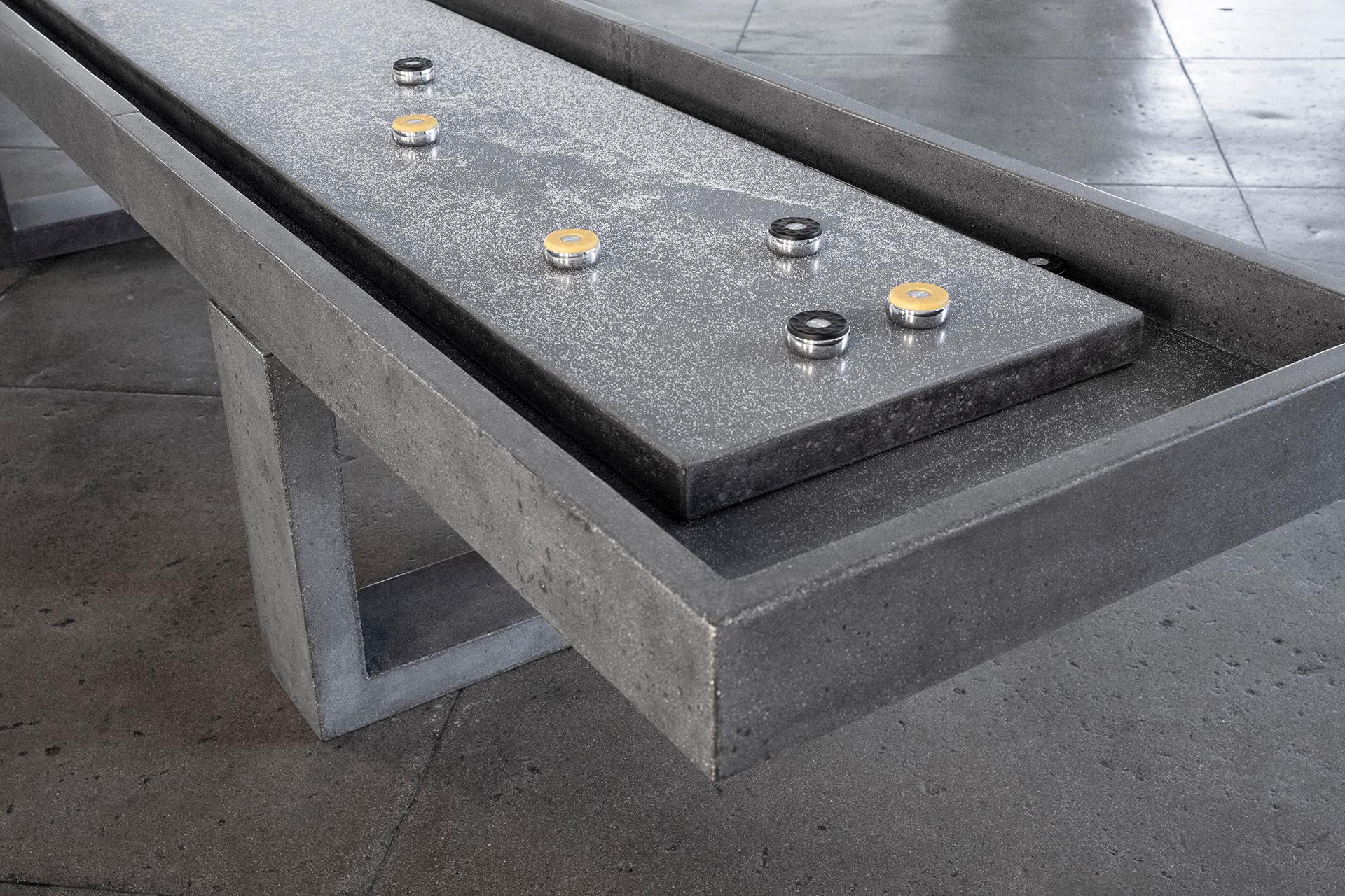 Der James de Wulf Shuffleboard-Tisch ist eine lebendige Ergänzung für jedes Spielzimmer. Der 9-Fuß-Tisch besteht aus mit Kohlefaser verstärktem Beton. Das sanfte Gleiten der Pucks über den fertigen Beton, gepaart mit dem brutalen Design des Tisches,