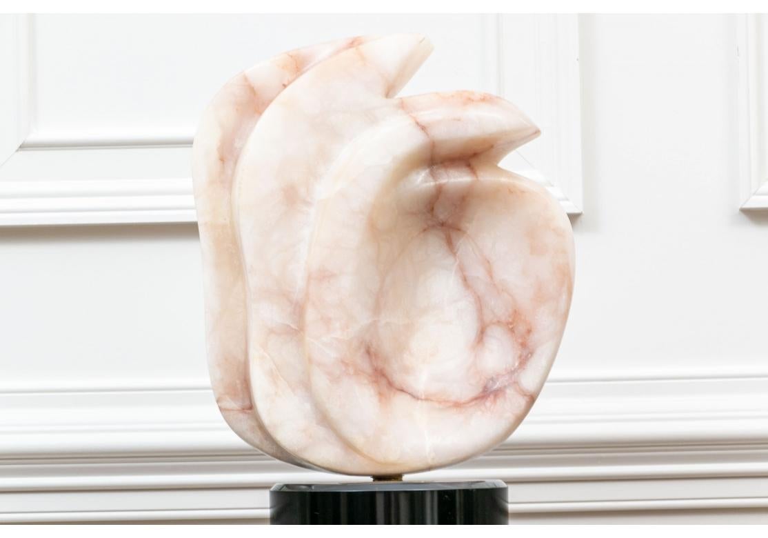 Abstrakte, geäderte Skulptur aus rosafarbenem Alabaster in einer doppelt geschwungenen, verbundenen Form mit oben sichtbaren Vogelköpfen. Montiert auf einem speziell angefertigten runden, drehbaren schwarzen Sockel, der auf einer schwarz lackierten