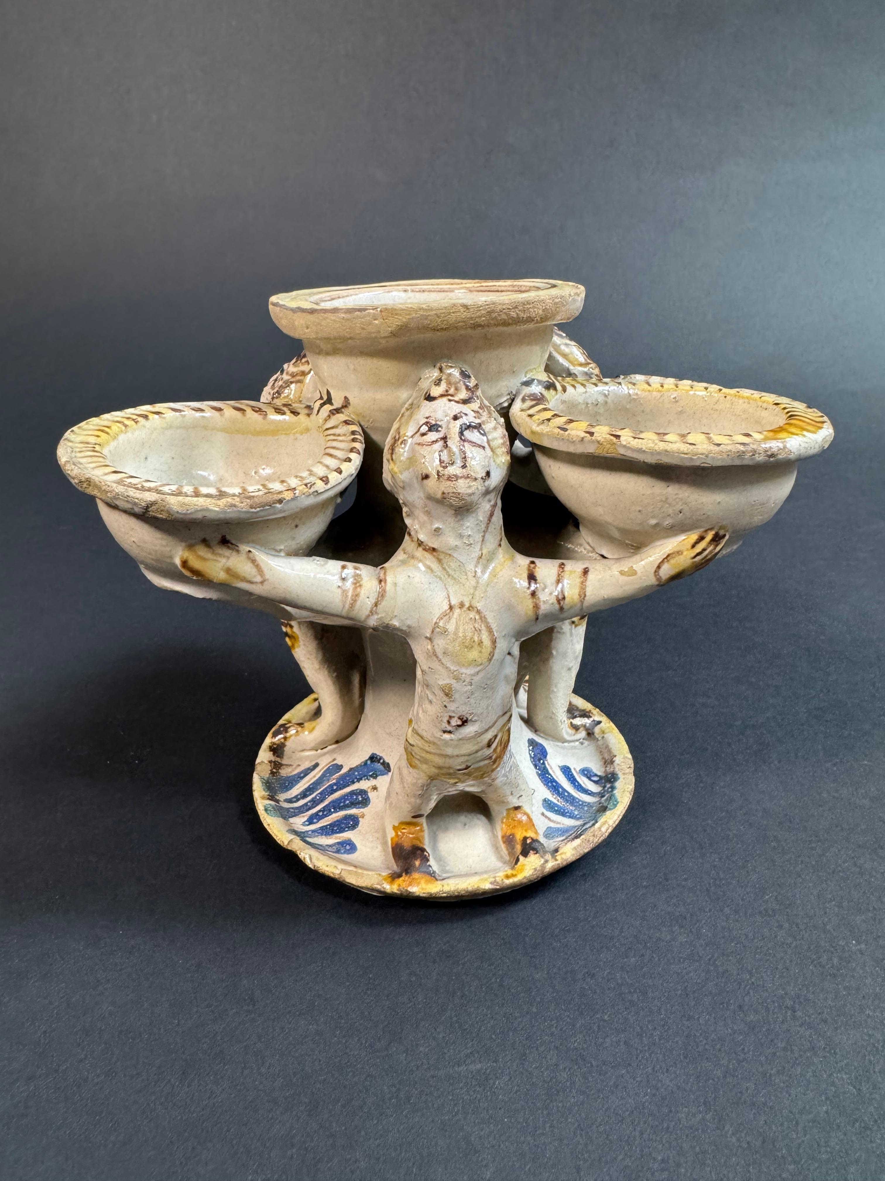 Saliera Laertina in maiolica della seconda metà del XVIII secolo. Questo oggetto, descritto nei cataloghi del patrimonio culturale, è composto da tre piccole vaschette circolari e una centrale più grande, sostenute da figure allegoriche