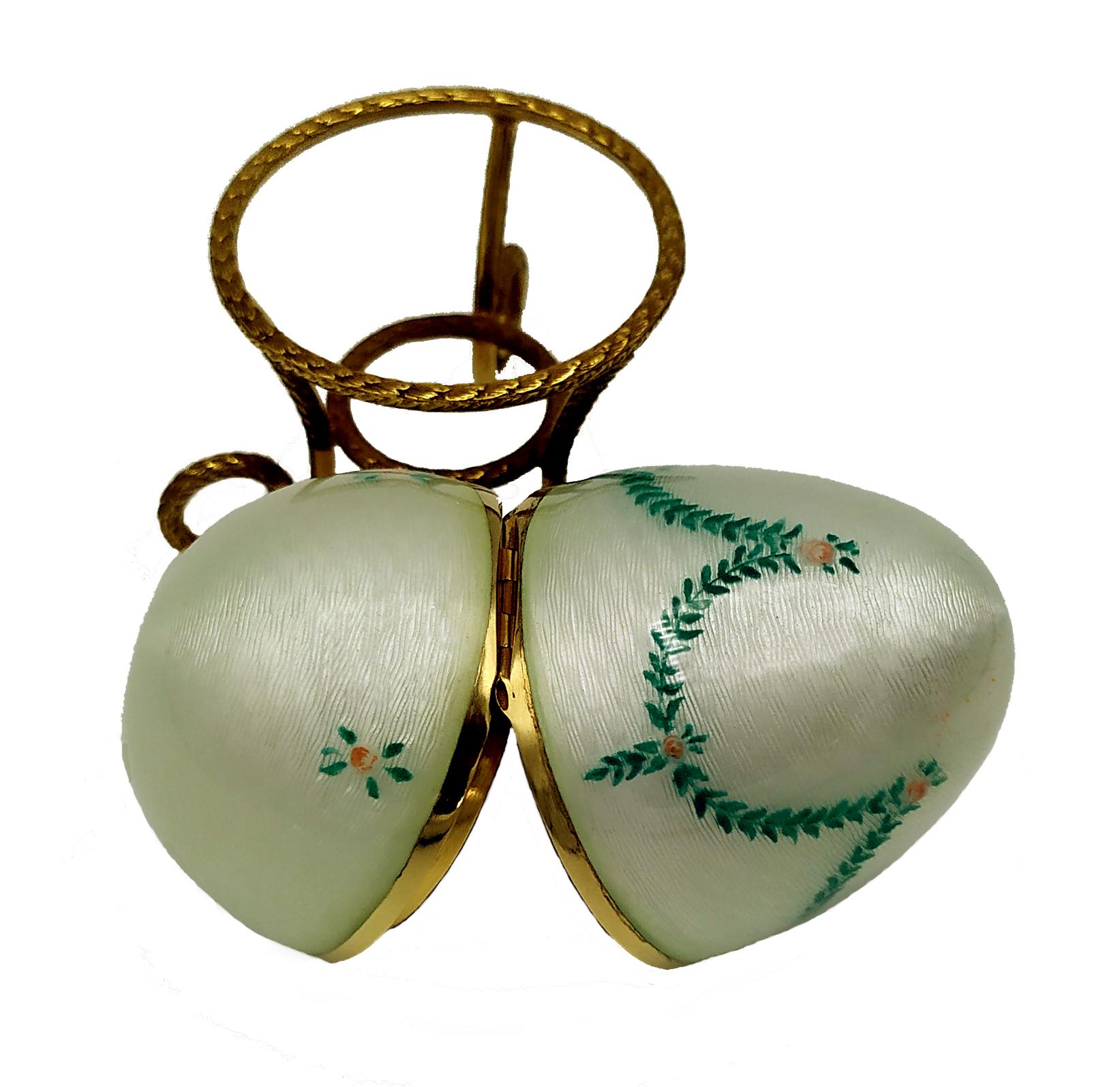 Egg in 925/1000 sterling silver gold plated with translucent fired enamel on guilloché with miniatures of hand-painted floral garlands resting on tripod. Viennese Art Nouveau style second half of the 19th century. Egg diameter cm. 5 cm high. 7,