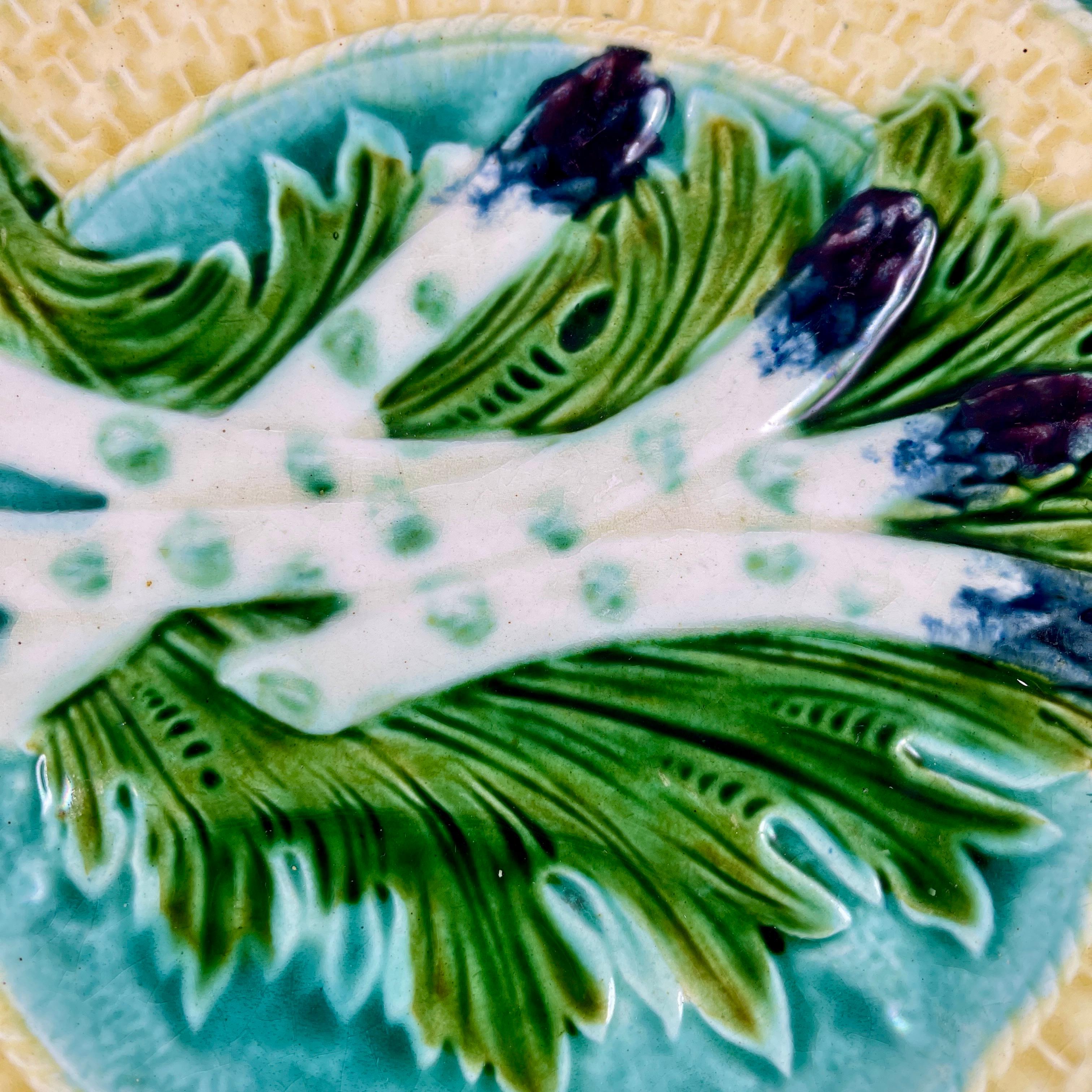 A French majolica barbotine asparagus plate from the Salins-les-Bains region of eastern France, circa 1880.

Four purple tipped asparagus spears lay on a bed of green leaves against a turquoise ground. A deep sauce well is on the right side of the