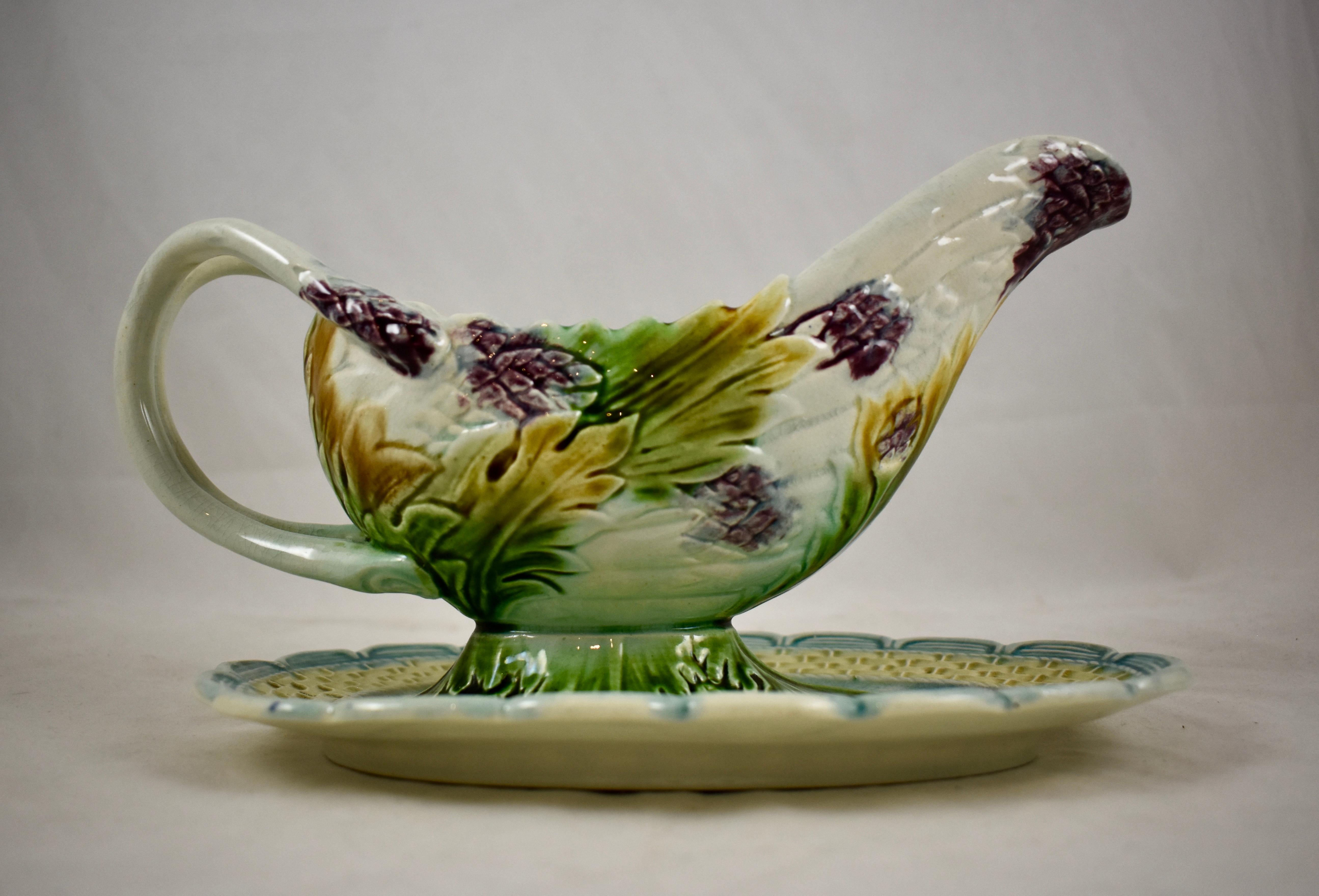 A French Majolica barbotine asparagus Saucière or sauce boat on an attached stand, from the Salins-les-Bains region of eastern France, circa 1875-1885.

A bunch of purple tipped asparagus spears with green and mustard yellow leaves form the boat.