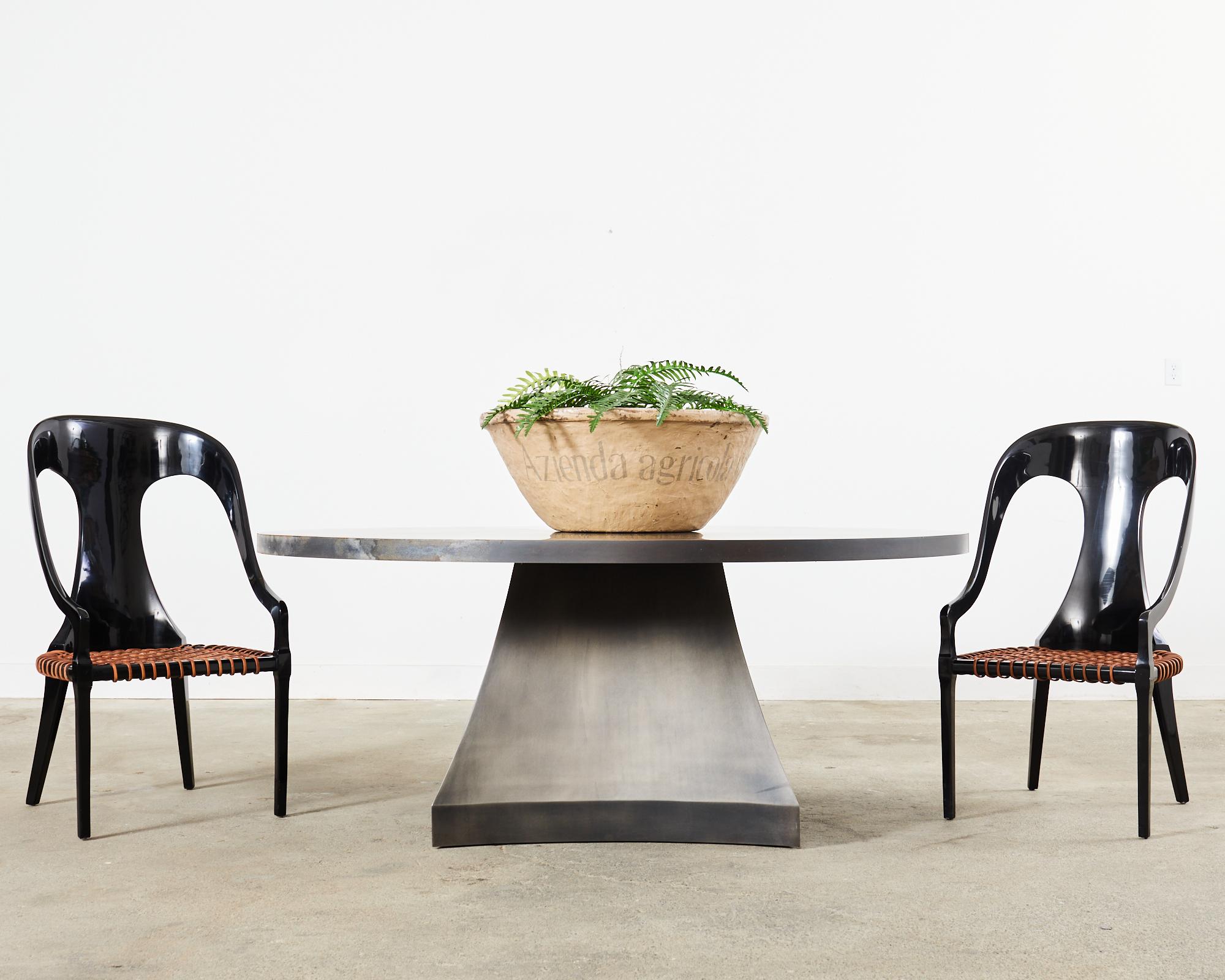 Imposing minimalist round iron dining table or grand center table designed by Sally Sirkin Lewis for J. Robert Scott. The modern bespoke table measures 75 inches in diameter supported by a sculptural four sided base. The pedestal has gracefully