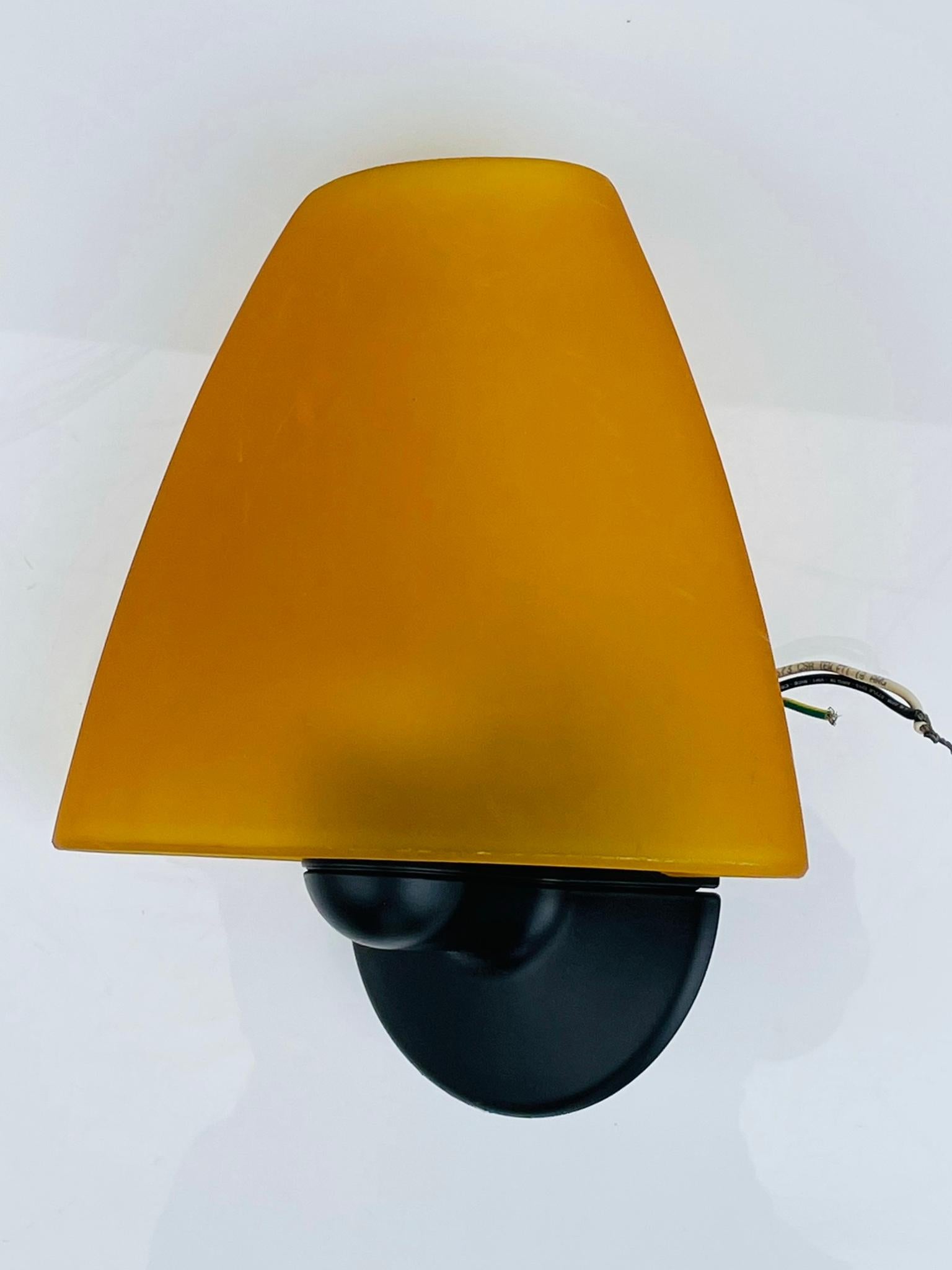 Vintage wall sconce designed by Marcello Ziliani in the 1990s and manufactured by Flos.
The Sally wall sconce has a glass shade and a metal bracket with a black finish.
The piece retains the Flos label.

One small chip the the upper