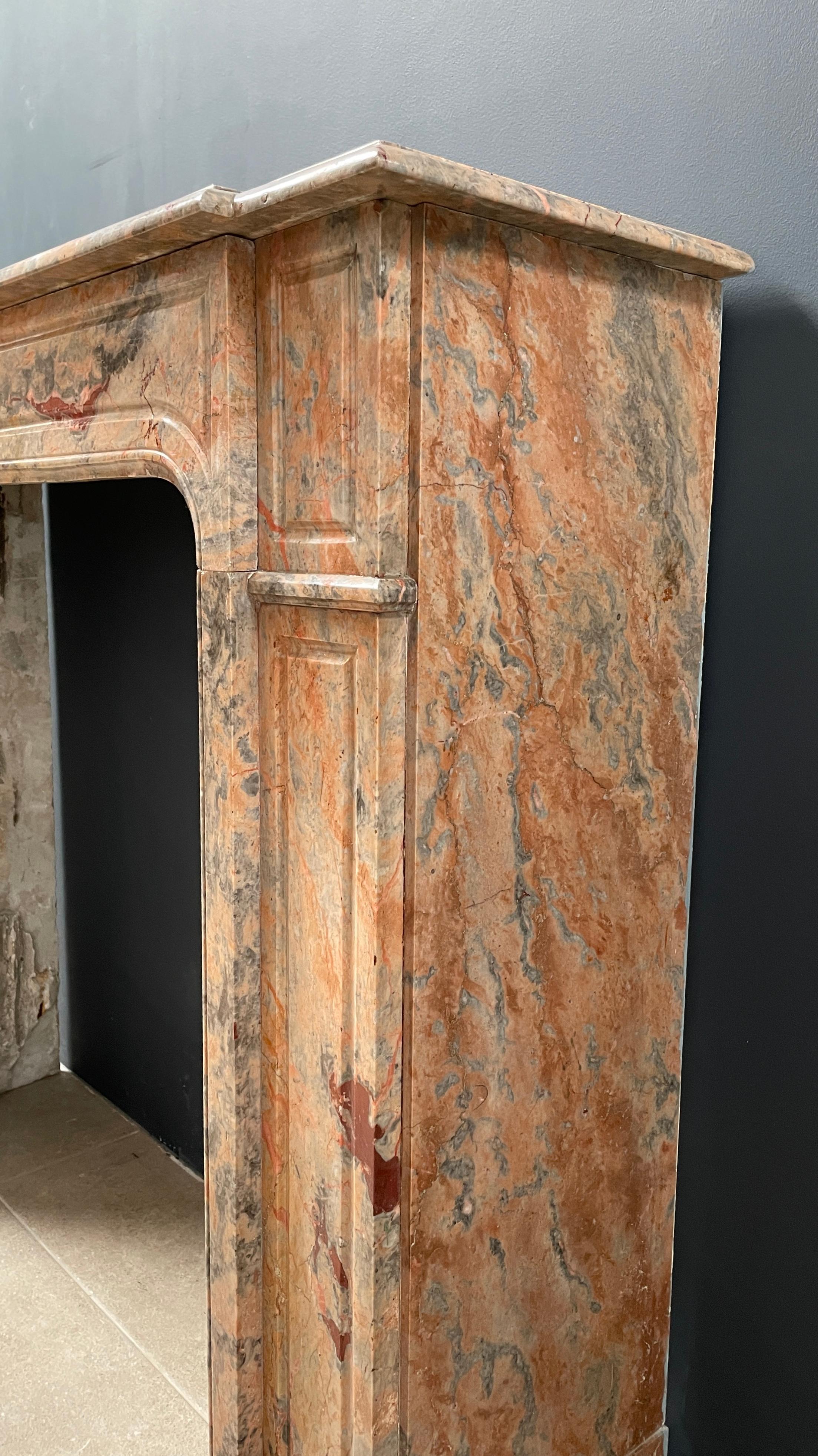 Beautiful antique salmon-colored marble front fireplace. Beautiful antique fireplace in special color. The consoles and the front are profiled. The consoles are slightly recessed in relation to the inner frame. The top follows the lines of the