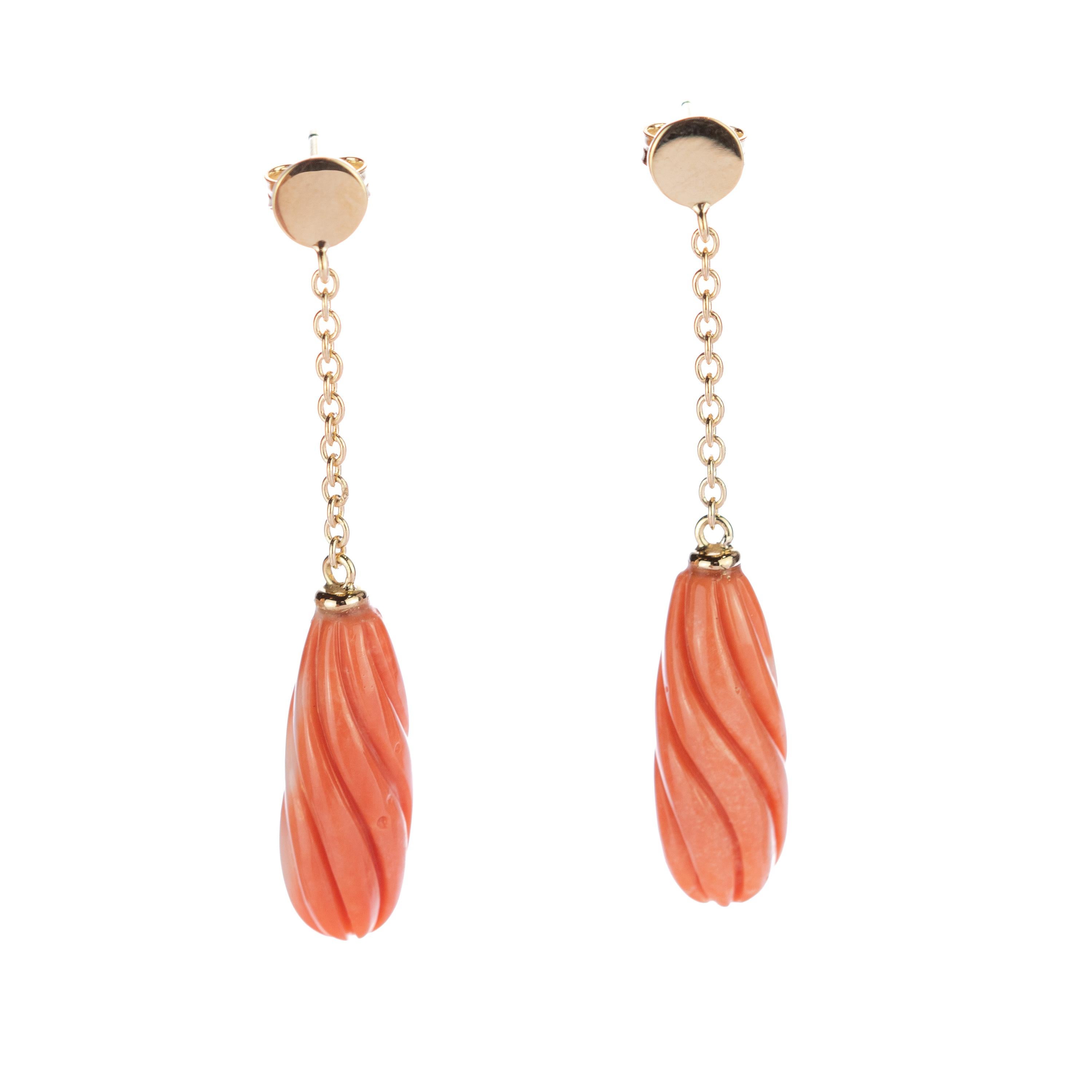 Exotic 23 carat coral earrings. The 18 karat yellow gold enhances the piece with a round circle that is connected to a delicate chain holding a beautifully carved and light salmon natural coral long shaped gem. Italians own the art of coral carving.