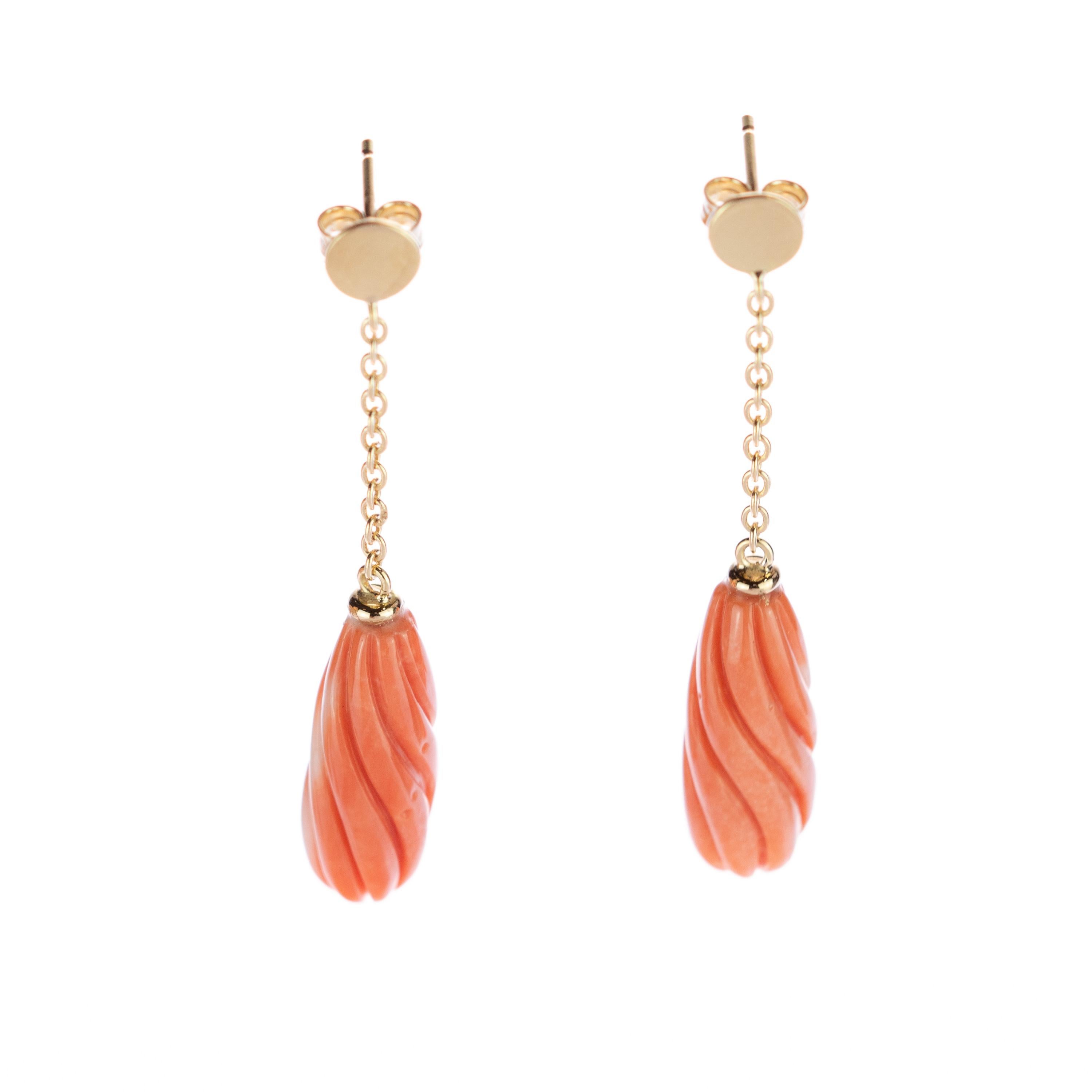 Exotische 23 Karat Korallenohrringe. Das 18-karätige Gelbgold veredelt das Schmuckstück mit einem runden Kreis, der mit einer zarten Kette verbunden ist, an der ein wunderschön geschnitzter, lachsfarbener, langgestreckter Edelstein aus Naturkoralle