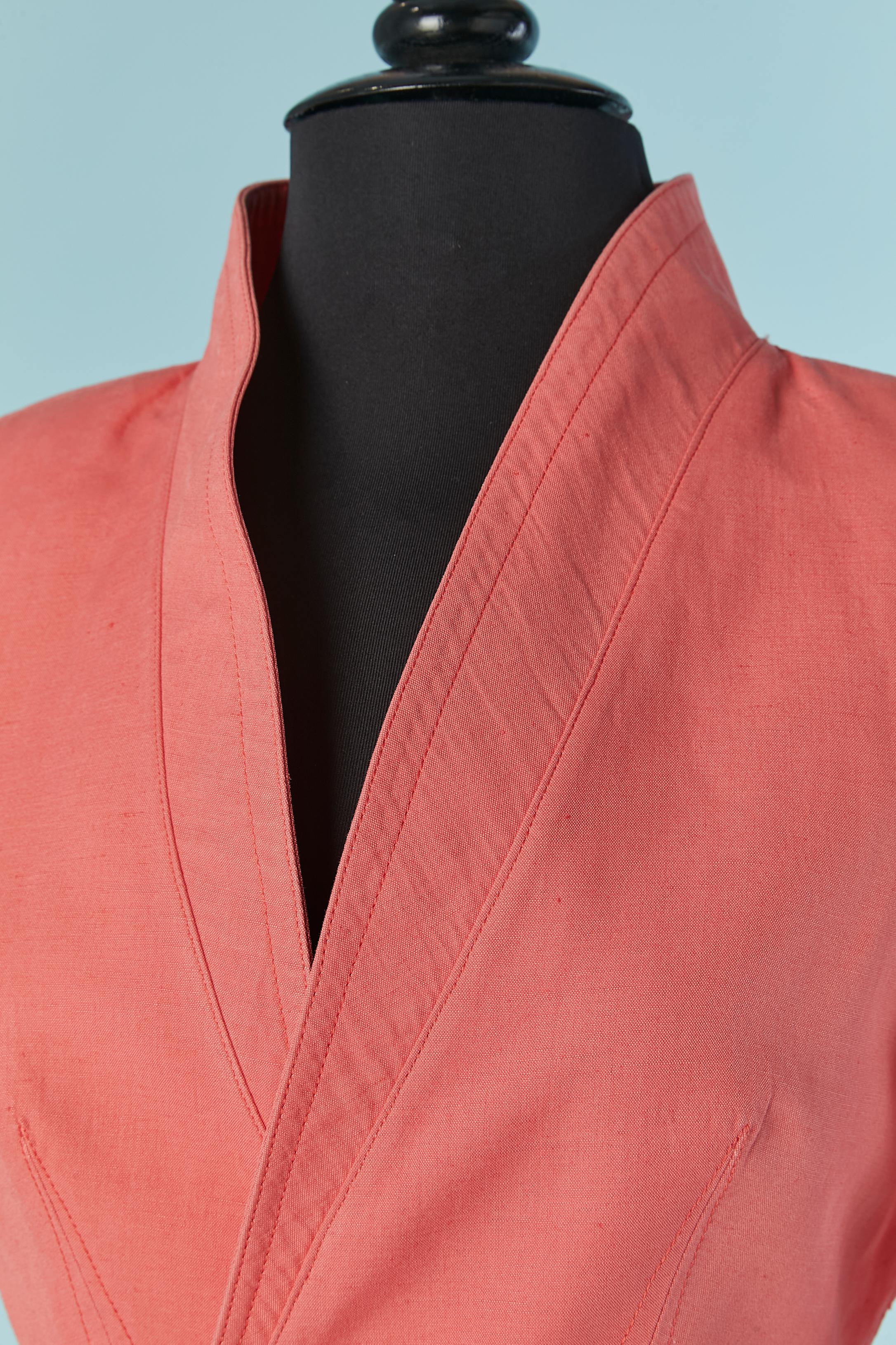Salmon pink skirt-suit with double-breasted jacket. Fabric composition: 40% linen, 60% rayon. Lining composition: acetate and cupro. 
Raglan sleeve, shoulder pad, open on the arm-pit. Snap closure on the middle front with metal embellishment.