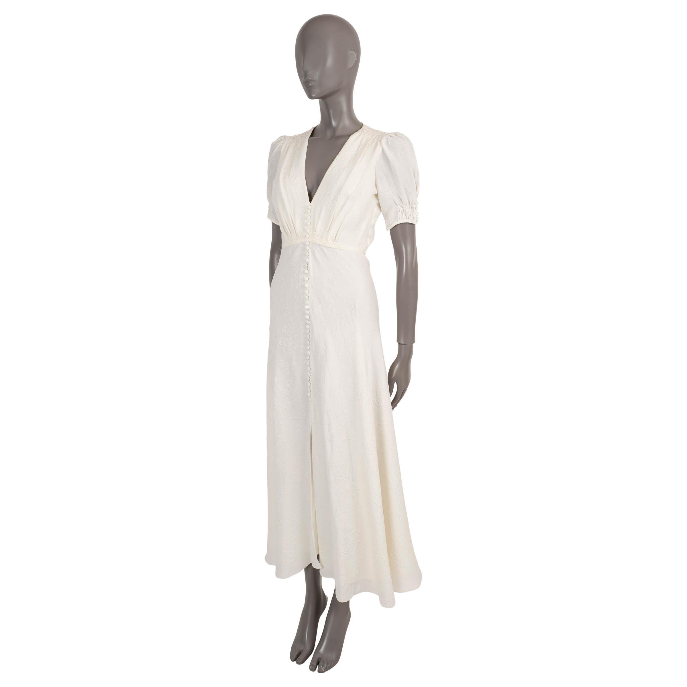 100% authentic Saloni Venyx Lea midi dress in cream floral jacwuard silk (100%). Features a fitted bodice, short puff-sleeves, V-neck, bias cut skirt with front opening and decorative buttons on the front. Opens with a concealed zipper in the back.