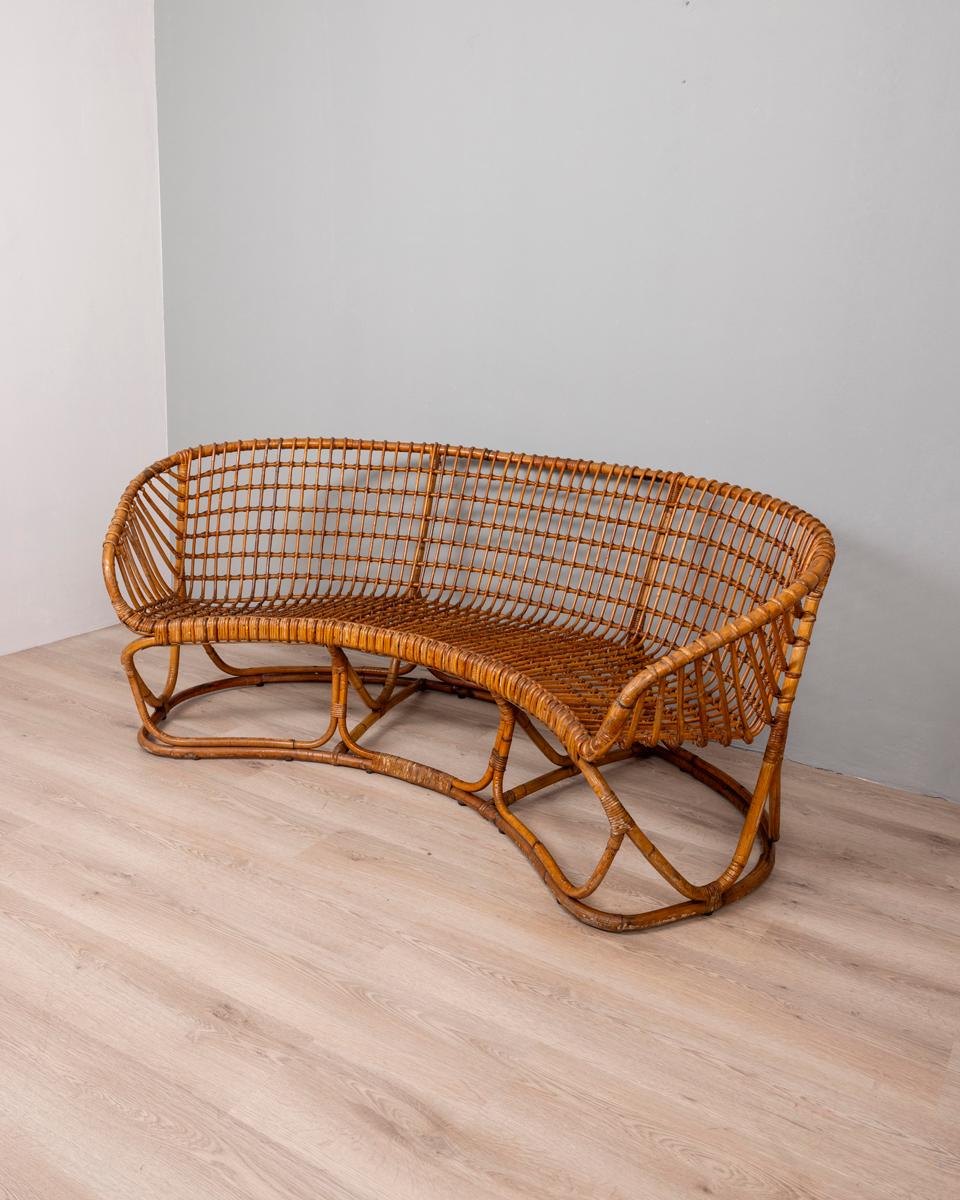 Salon en bambou et rotin composé d'un canapé incurvé, de deux fauteuils et d'une table basse en verre. Design italien, années 1950.

ÉTAT : En bon état, présentant des signes d'usure dus au temps.

DIMENSIONS :
Canapé : Hauteur 77 cm ; Largeur 185