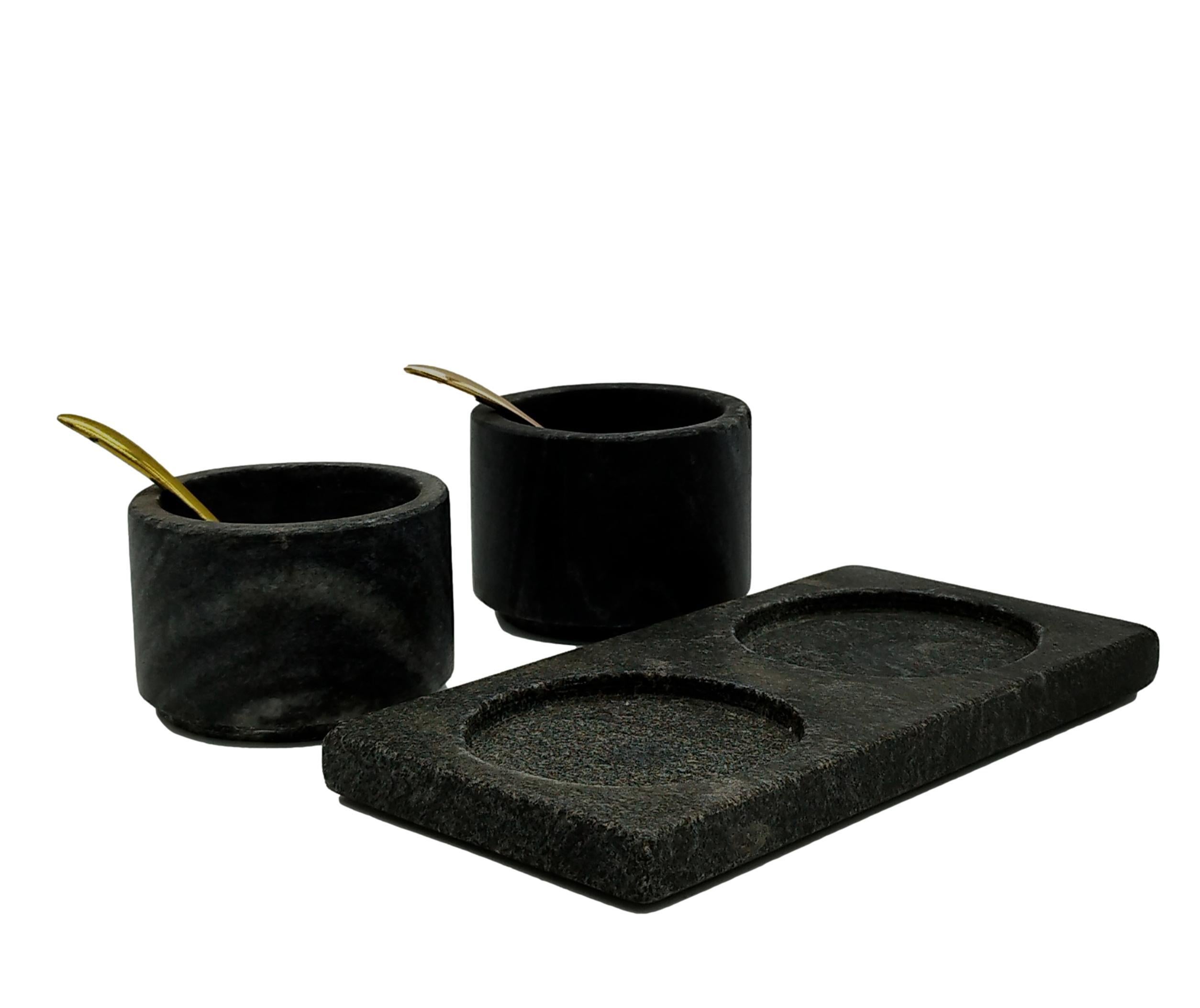 Black marble salt and pepper spice containers with brass spoons.
 