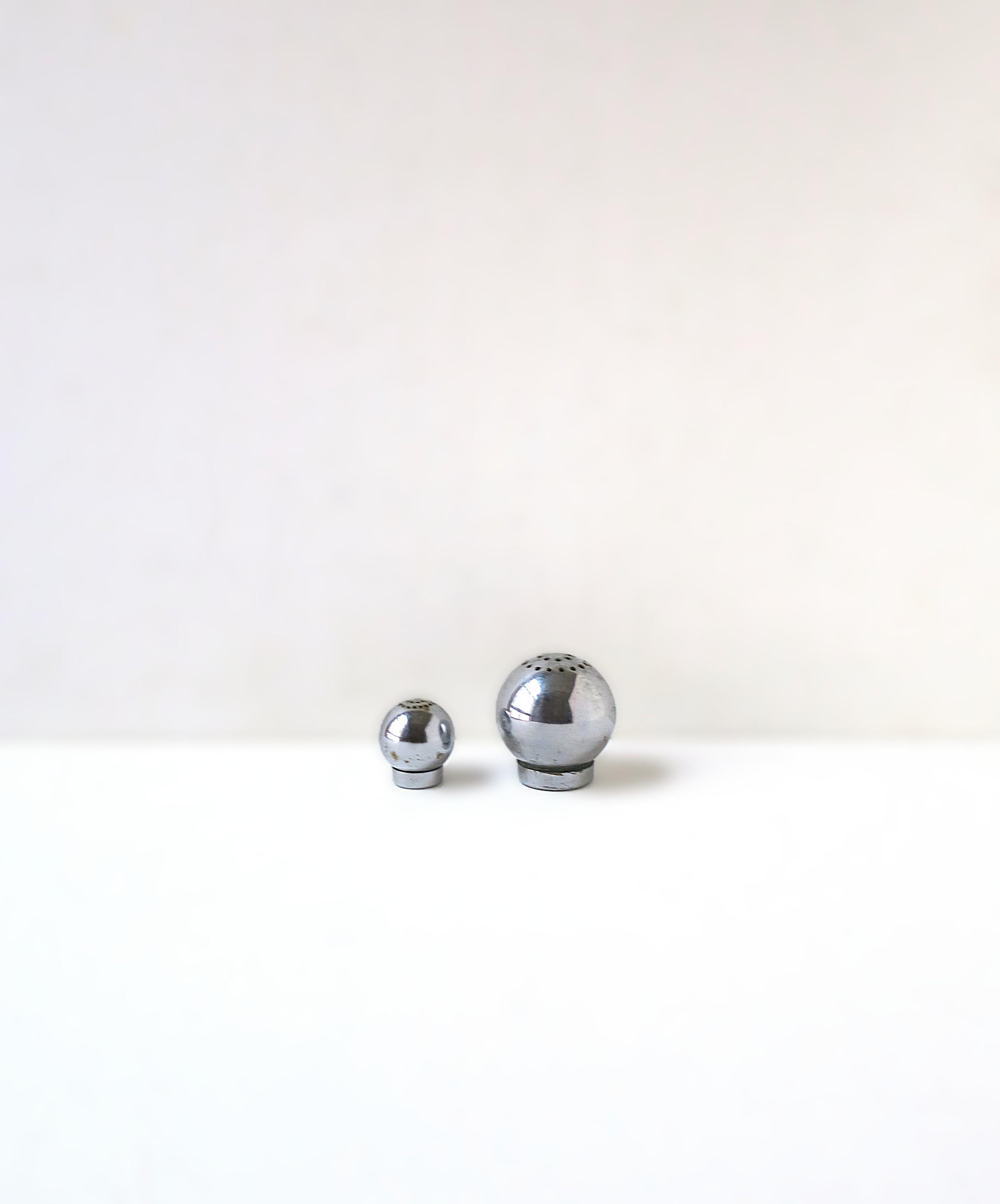 A rare and chic set of American chrome plate brass sphere salt and pepper shakers, Modern/Modern Streamlined/Art Deco design period, by designer Russel Wright for Chase Brass and Copper Co., 1935, USA. This set/pair are chrome plated brass in a ball