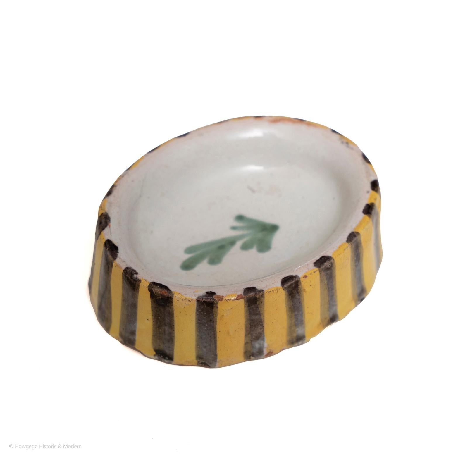 Rare surviving small piece of early tableware. Suitable for everyday use as a charming piece of history for the dining table.

French faience salt. Oval shape with a leafy sprig in the centre and the edge painted with blue and yellow stripes. In