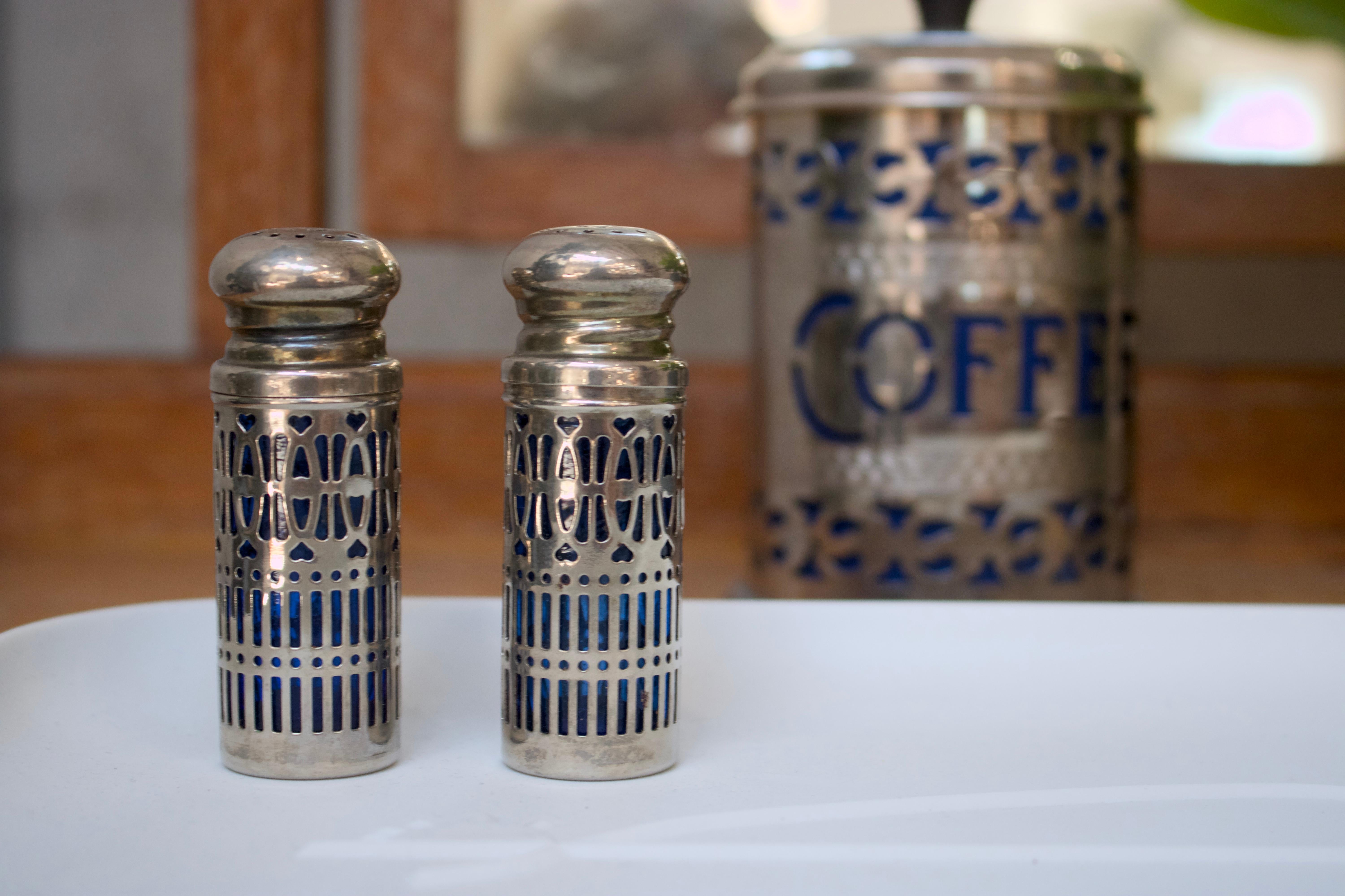 Juego de salero y pimentero de época con filigrana de plata y preciosas inserciones azules. Estas piezas combinan perfectamente con nuestro bote de café vintage de origen similar.