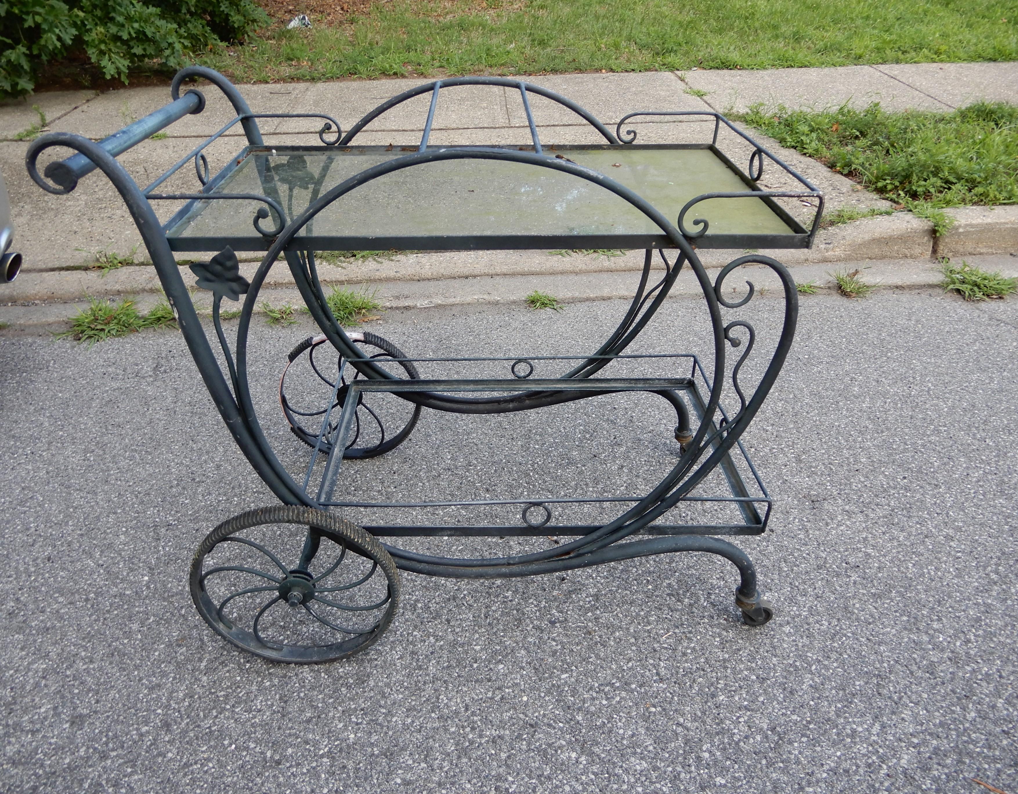 A Salterini wrought iron bar or tea cart, in the desirable Mt Vernon pattern. The tea cart needs a piece of glass for the bottom shelf. The top shelf is there and needs a cleaning. This cart is the model used in the TV series Mad Men wth John Hamm,